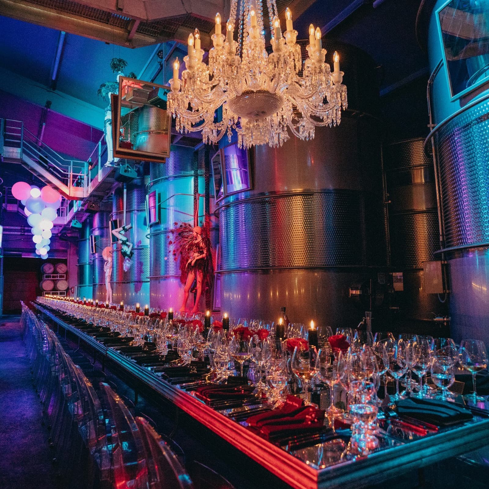 Elegant dining setup with chandeliers in industrial hall.