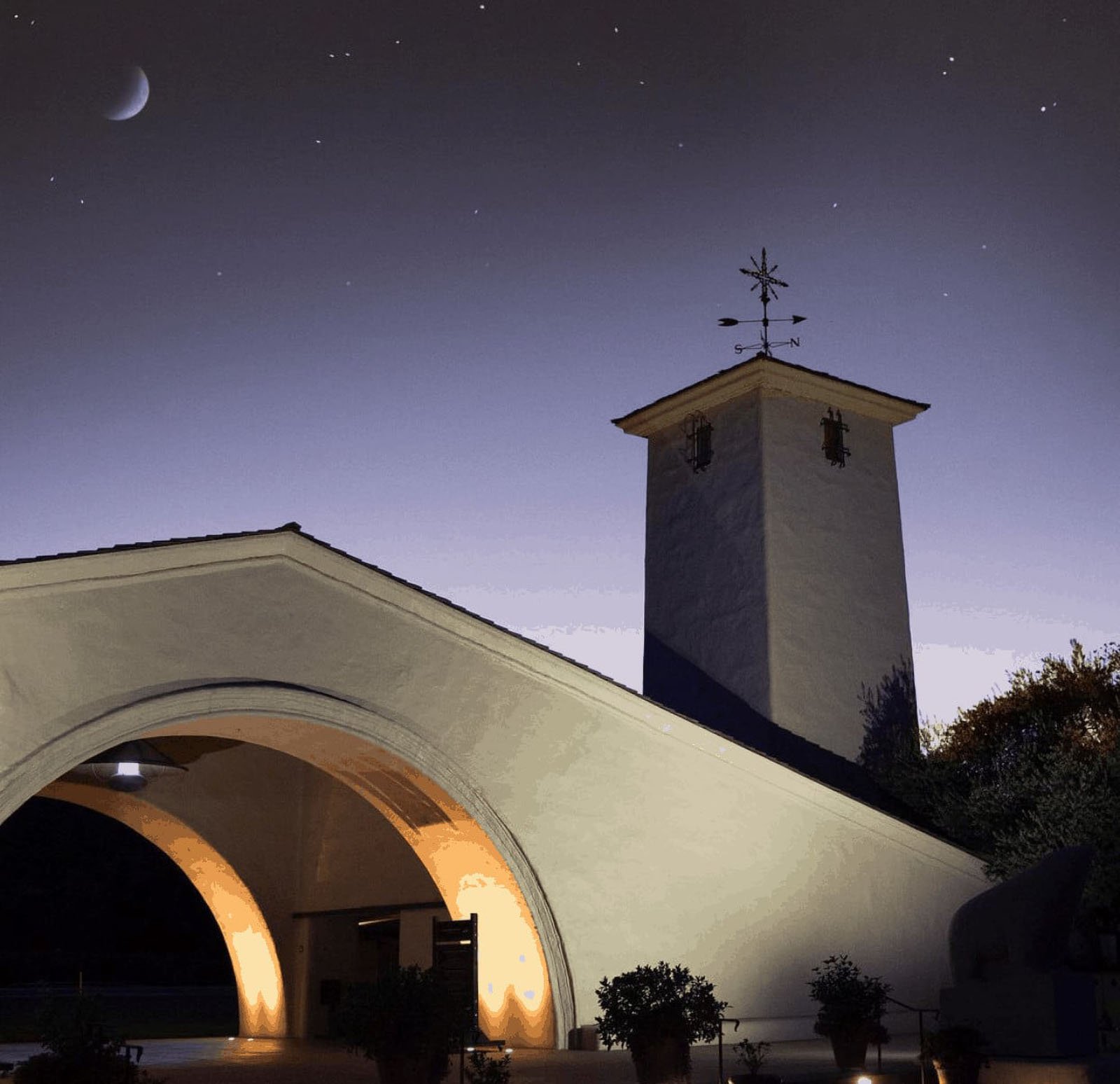 Illuminated building with arches and tower at dusk.