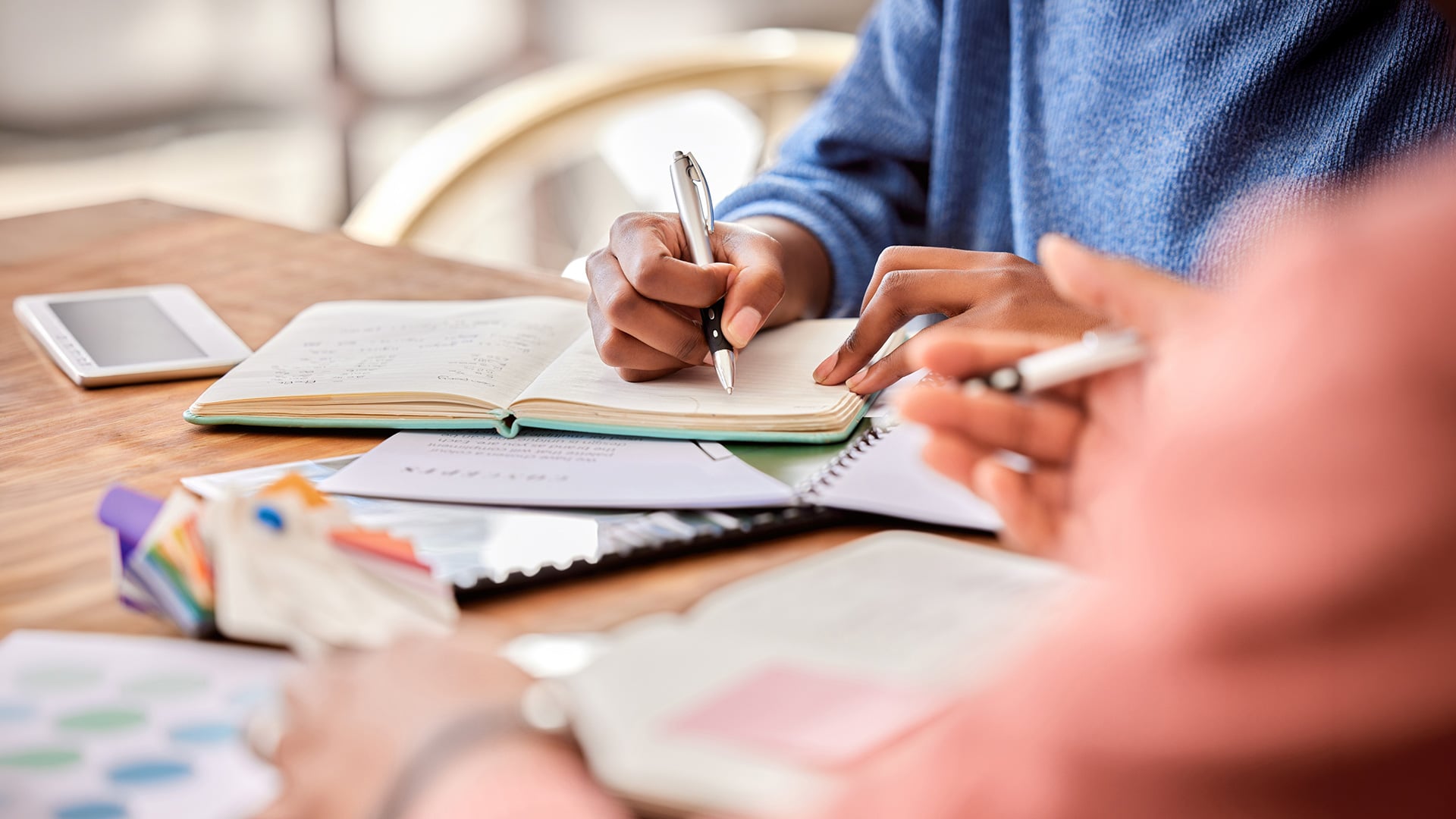 Students writing in notebooks at study table