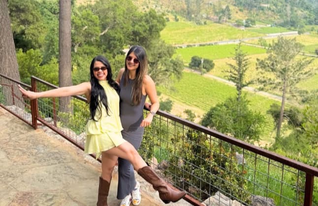 Two women posing at scenic vineyard overlook