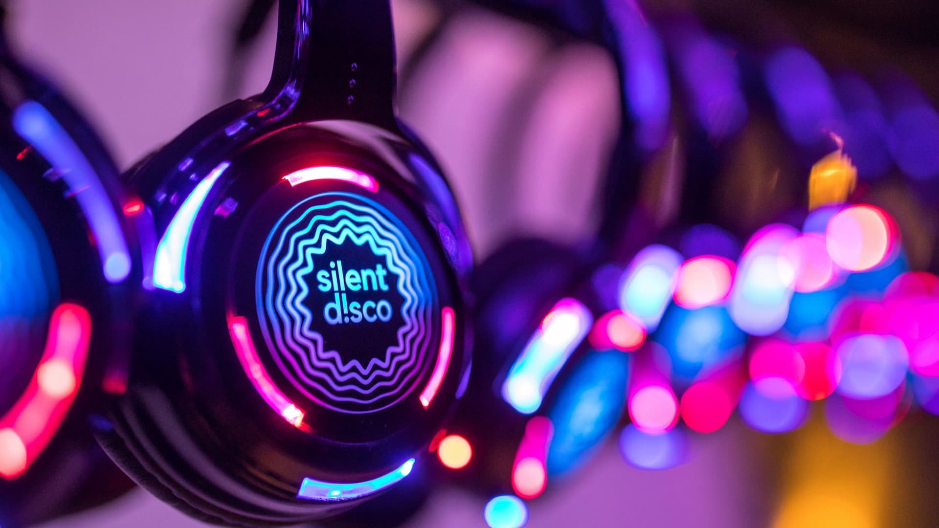 Colorful silent disco headphones glowing in dark.