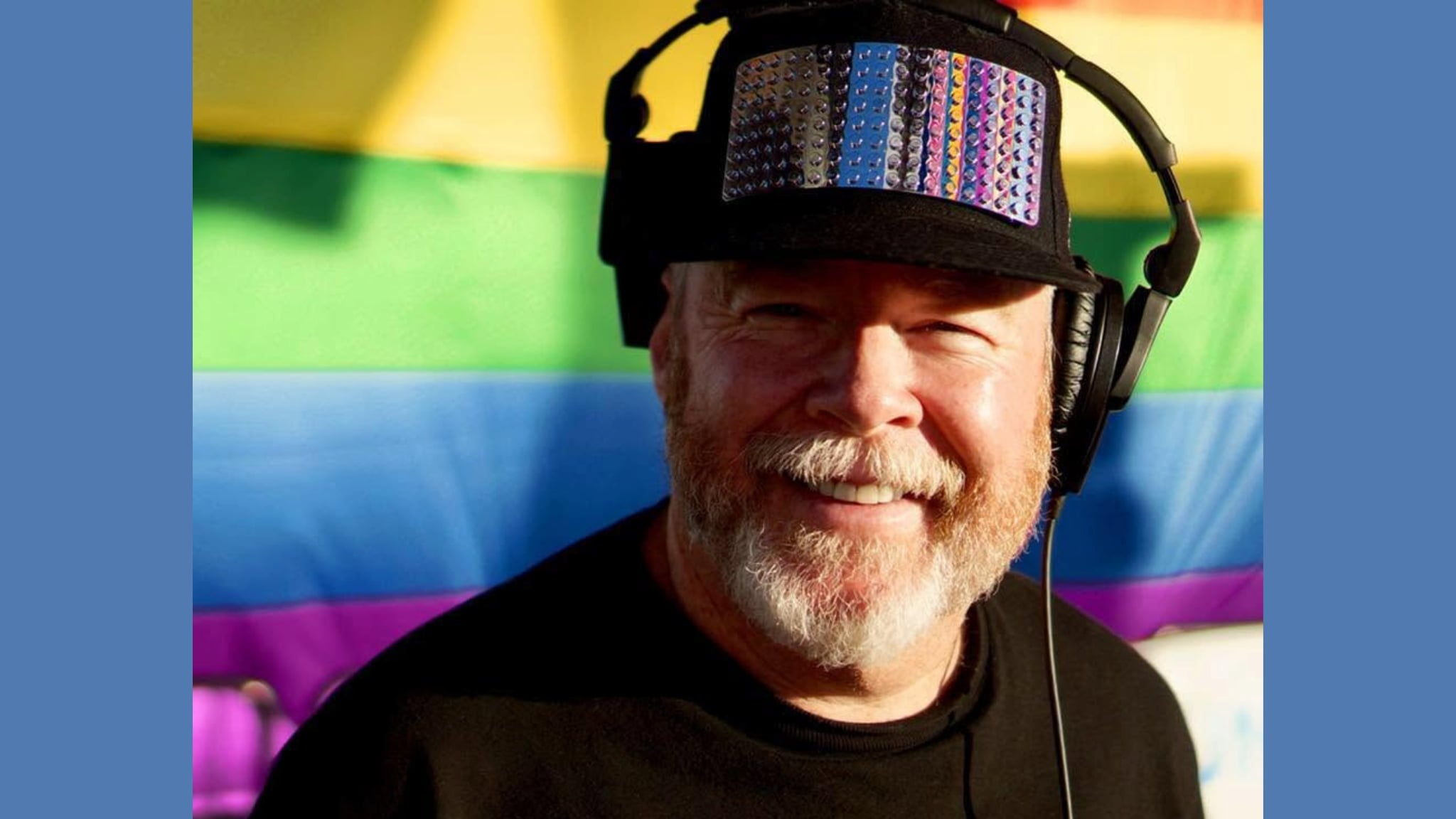 Smiling bearded man wearing headphones and decorated cap