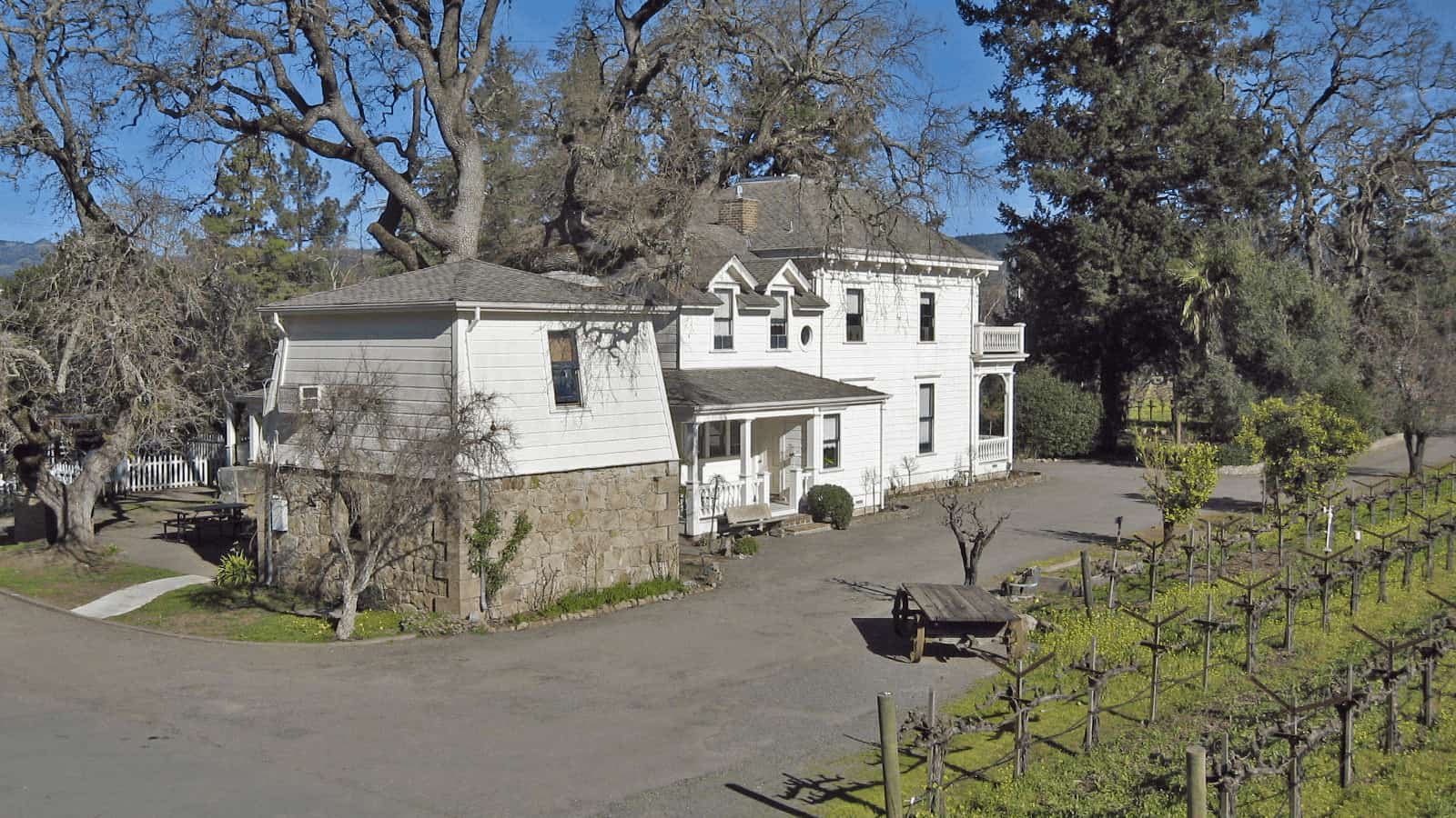 Historic white house beside vineyard and trees