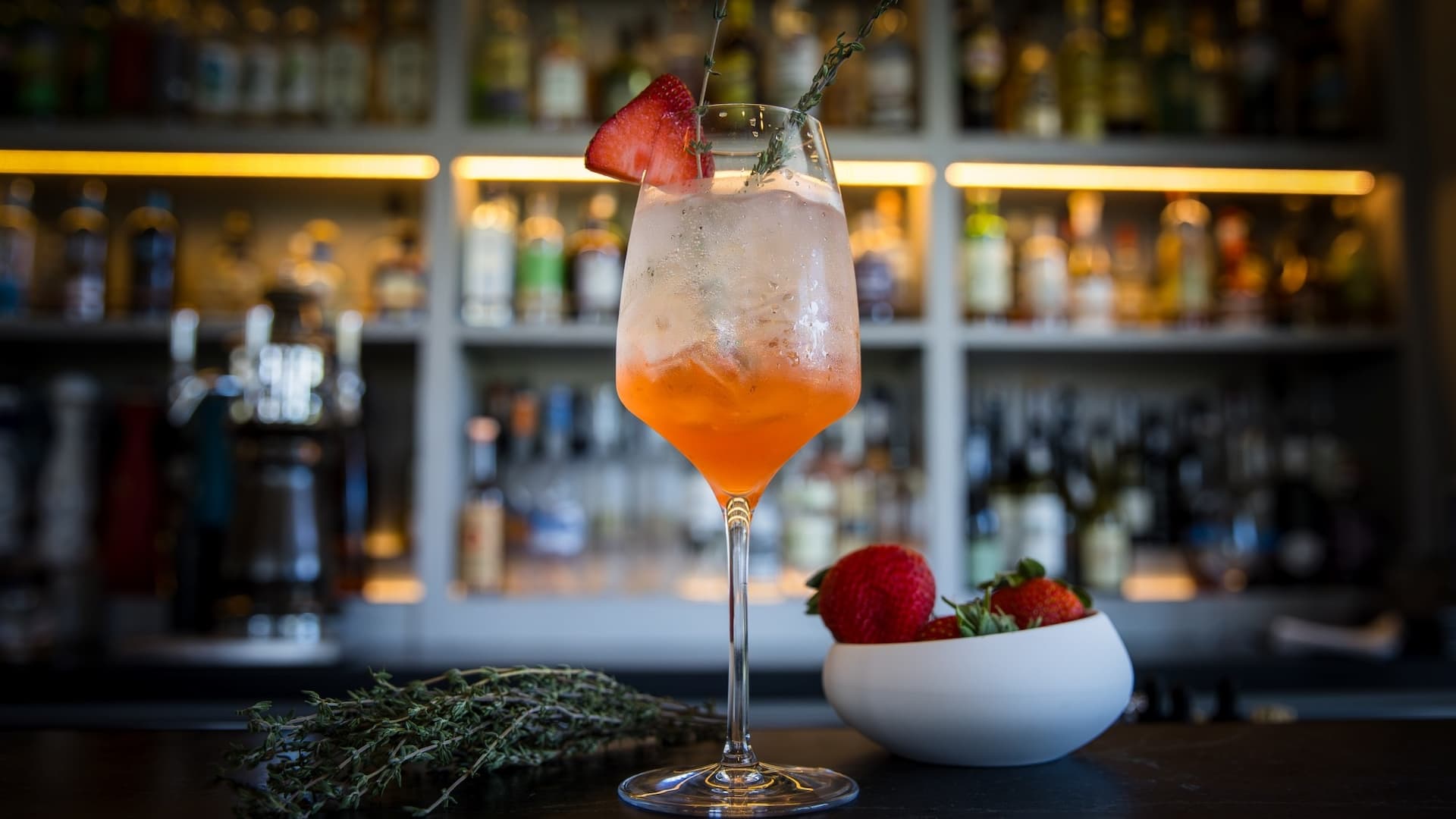 Refreshing cocktail with strawberries and herbs at bar.