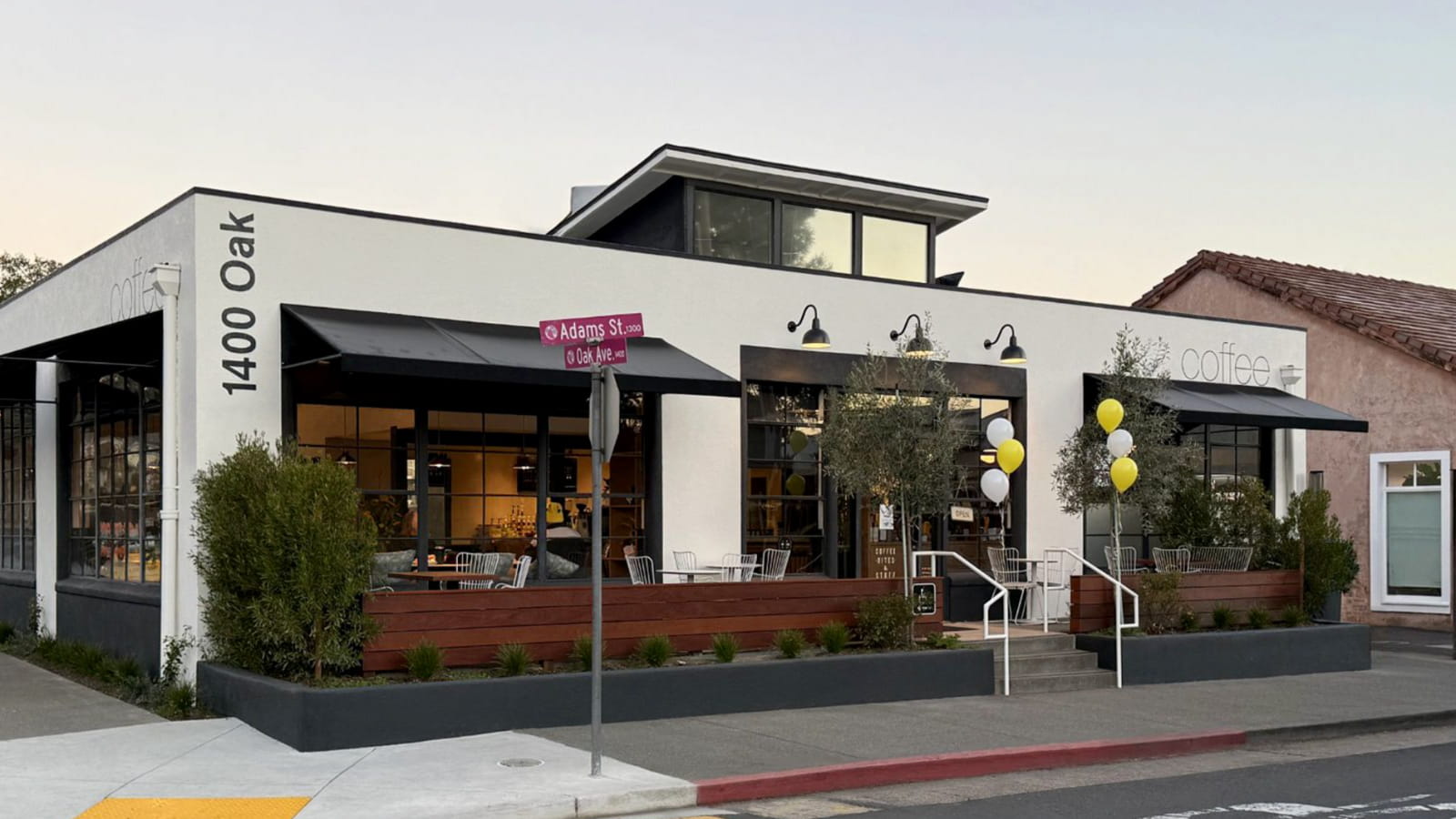 Modern coffee shop on corner street, white exterior.