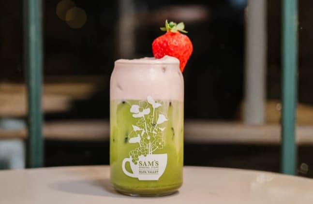 Matcha latte with strawberry garnish in glass jar