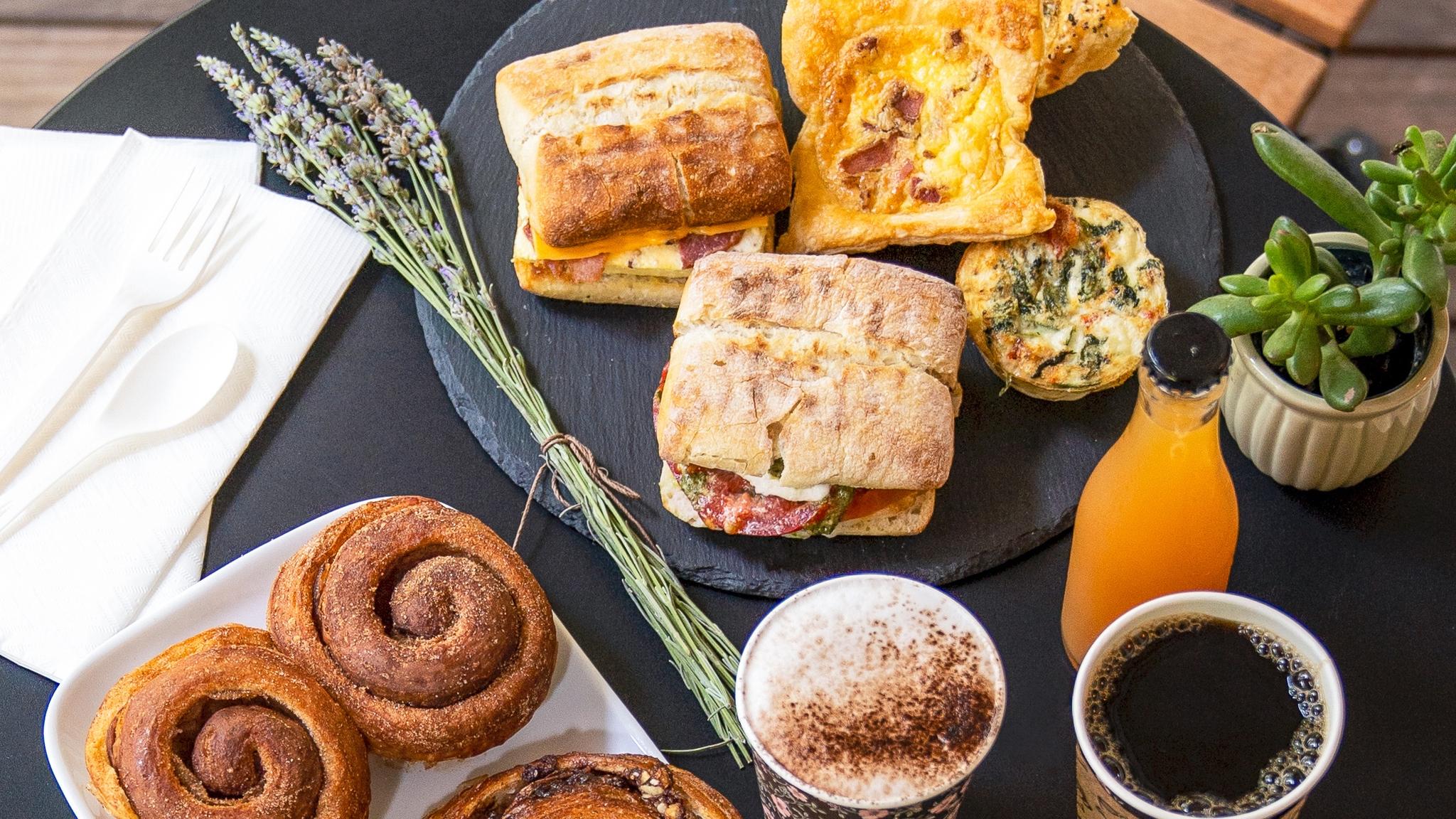 Breakfast spread with sandwiches, pastries, coffee, and juice