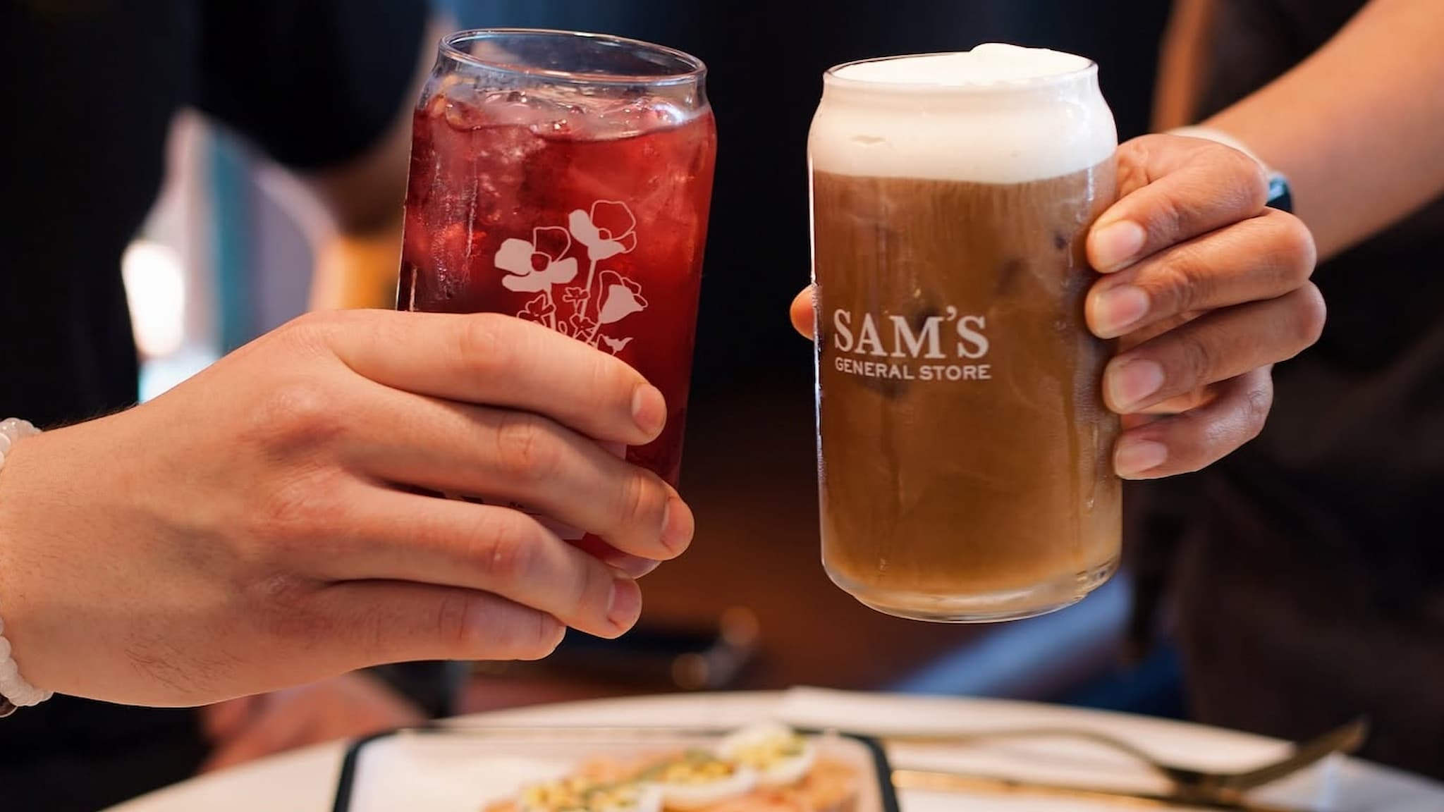 Two people toasting with beer and red cocktail
