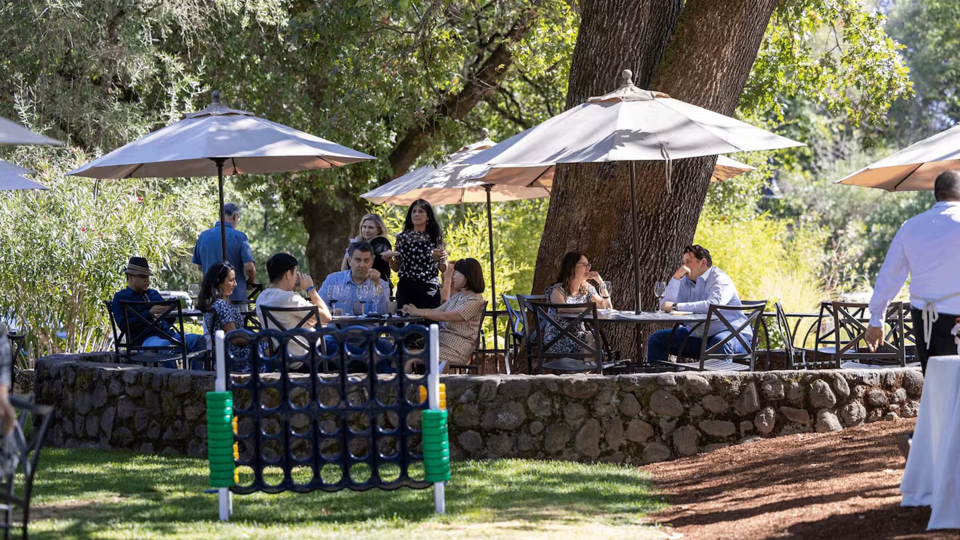 Outdoor dining under umbrellas in a garden setting.