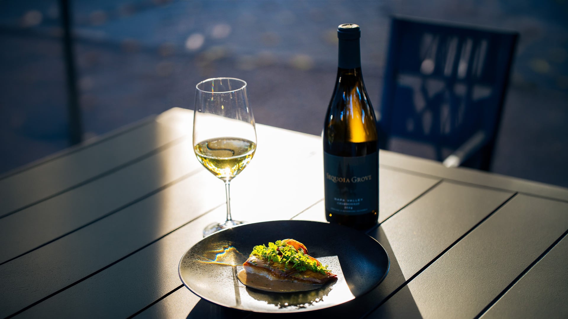 White wine, bottle, and plated fish in sunlight
