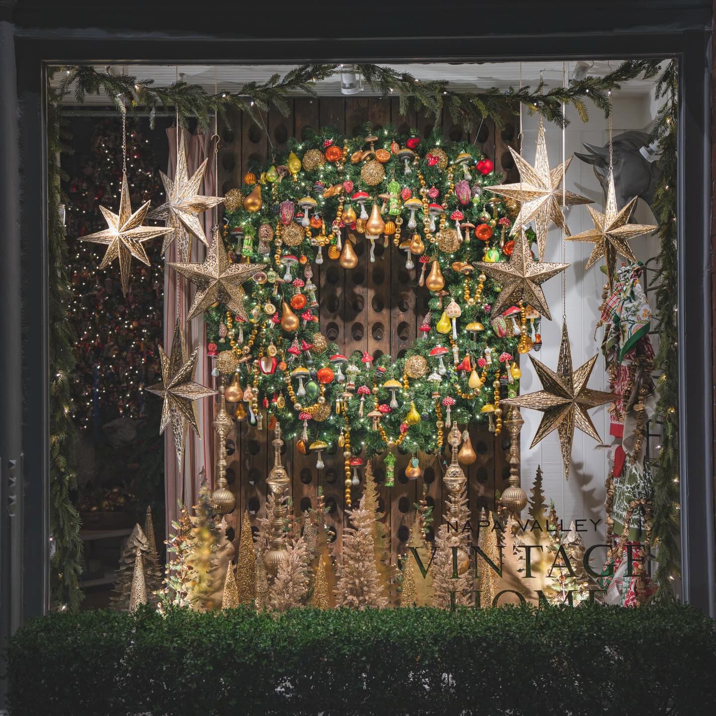 Festive holiday window display with wreath, stars, and ornaments