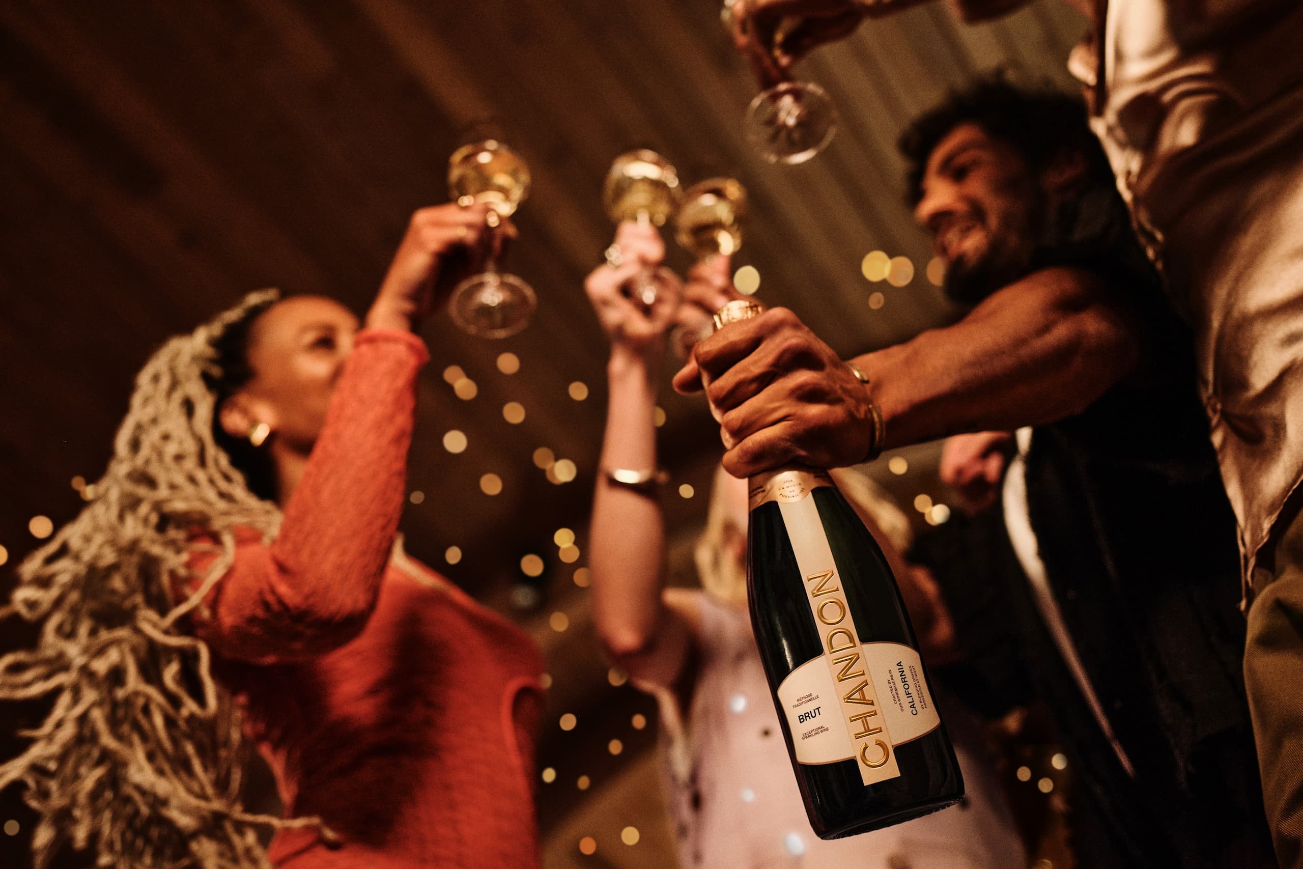 Friends celebrate with champagne bottle and raised glasses