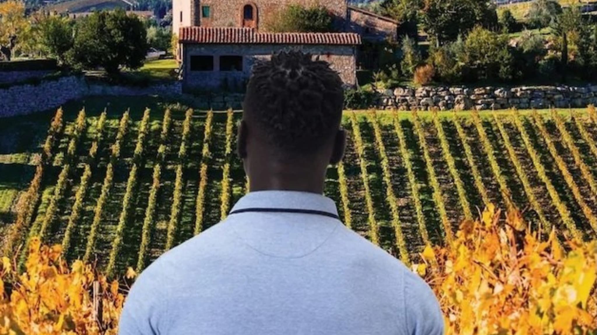 Man overlooking vineyard and rustic countryside estate