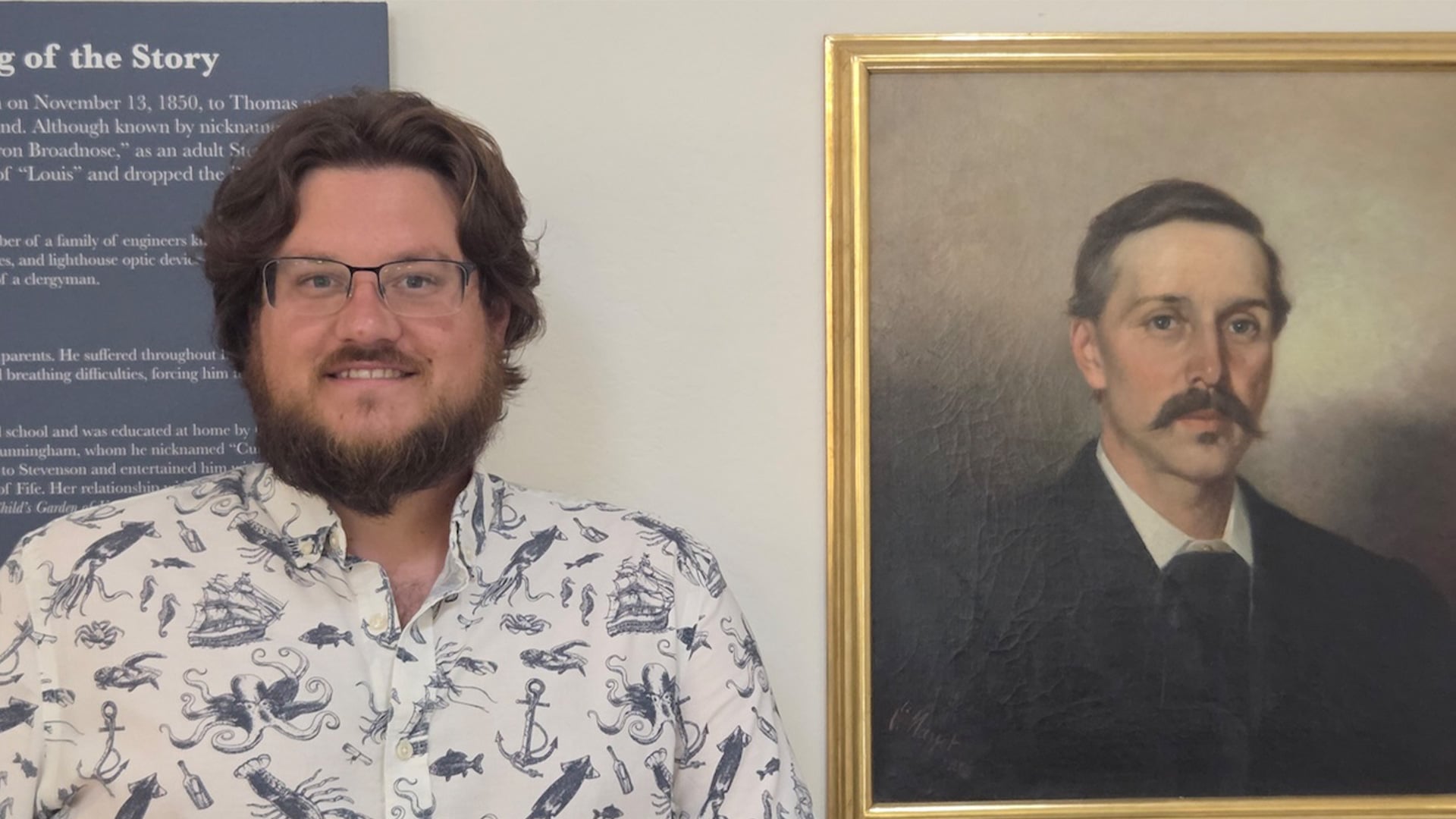 Man standing beside framed portrait painting indoors