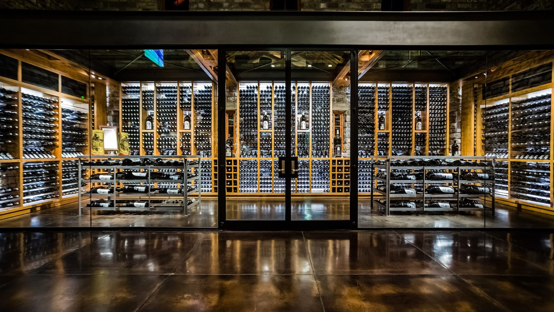 Modern wine cellar with bottles and glass doors.