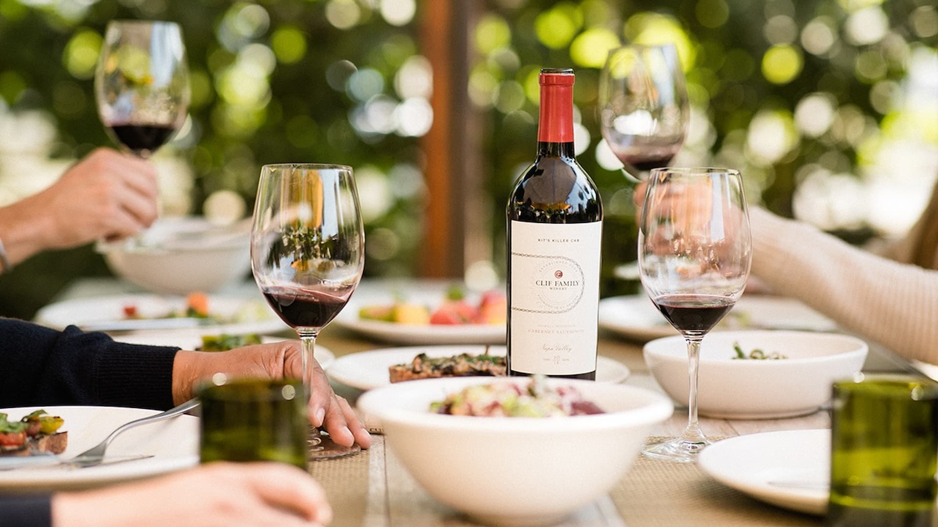 Red wine bottle and glasses on dining table.