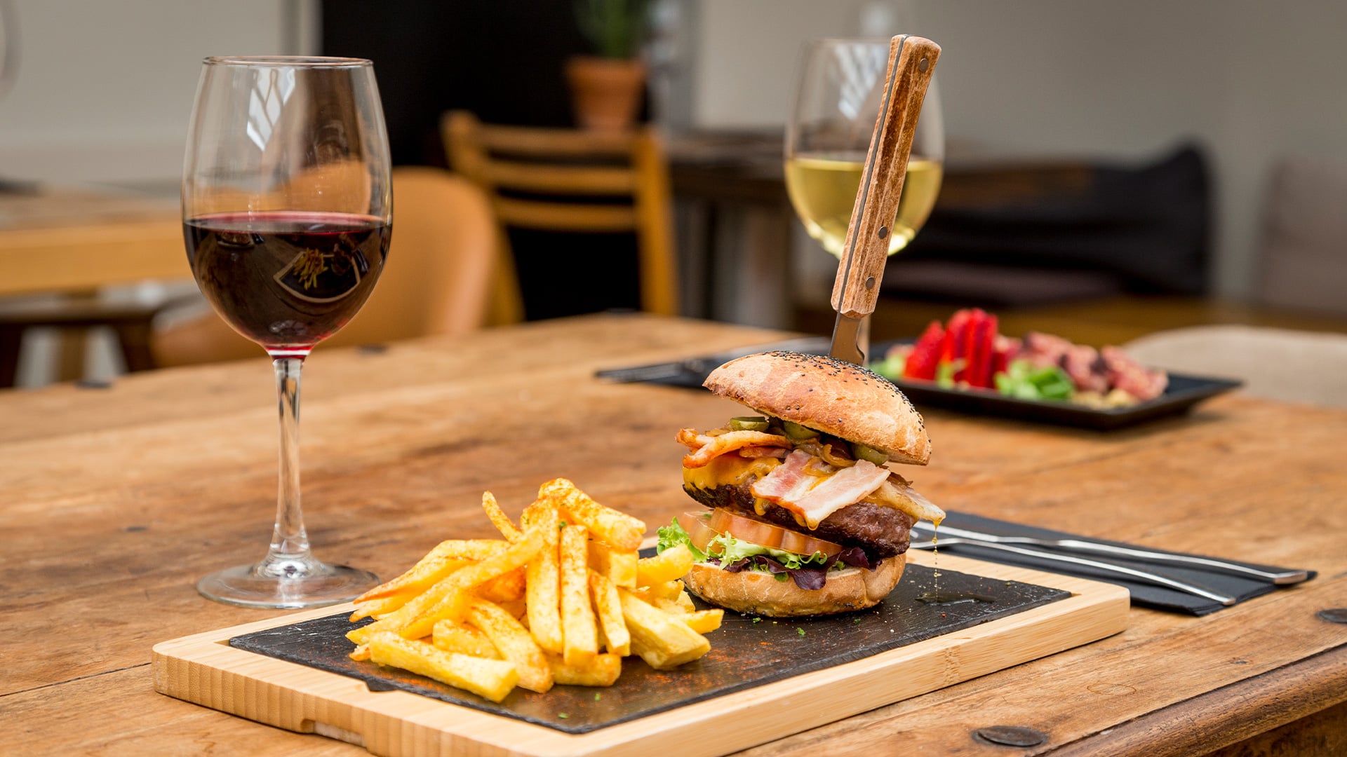 Gourmet bacon cheeseburger with fries and red wine