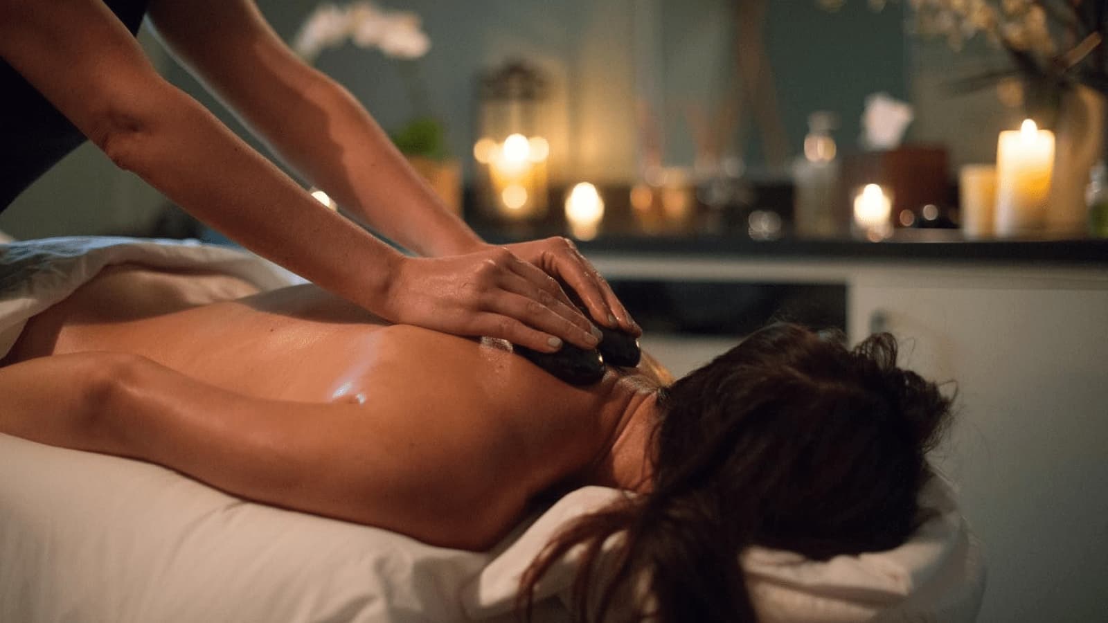 Person receiving hot stone massage in spa.