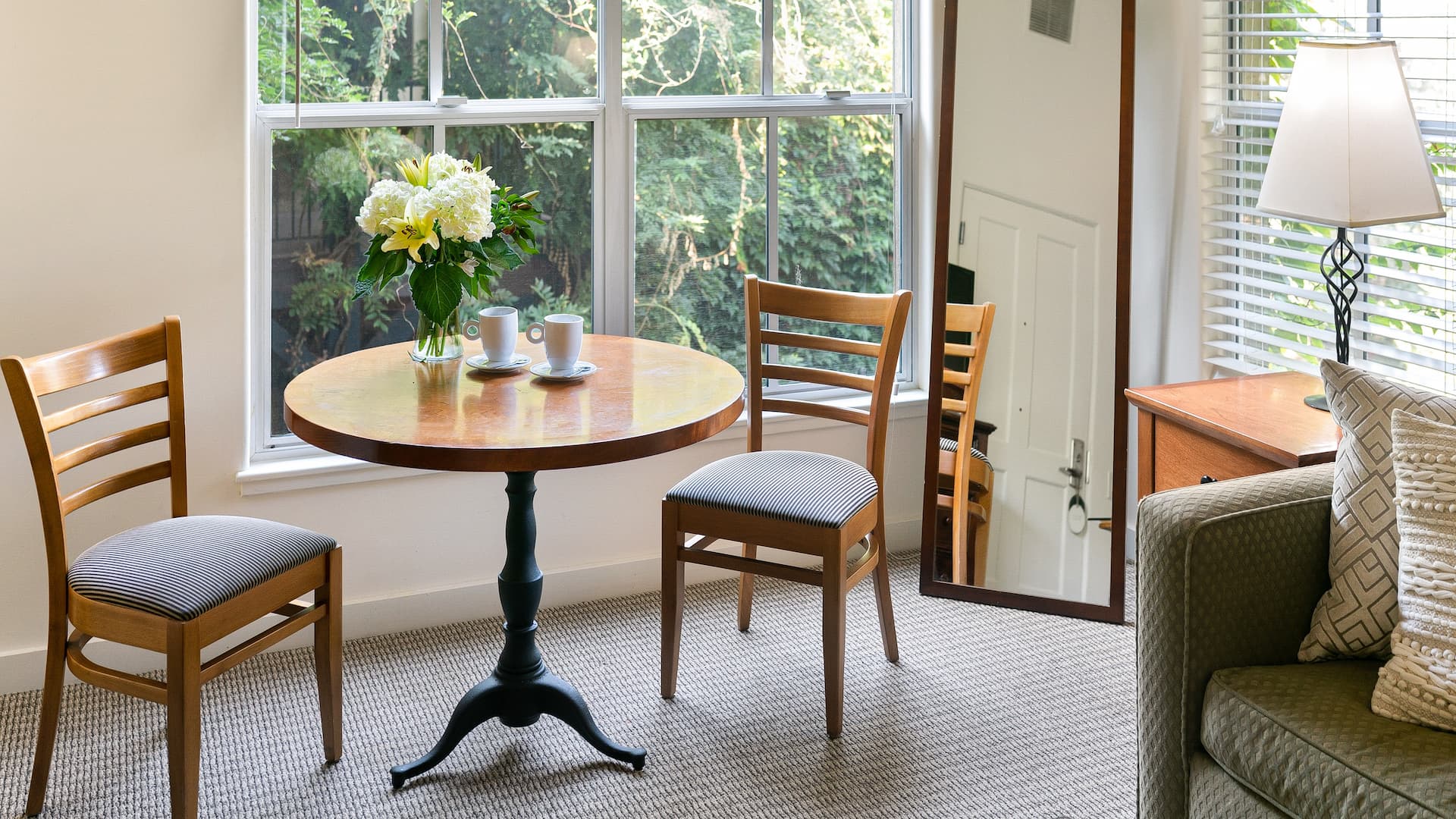 Cozy room with table, chairs, flowers, and mirror.