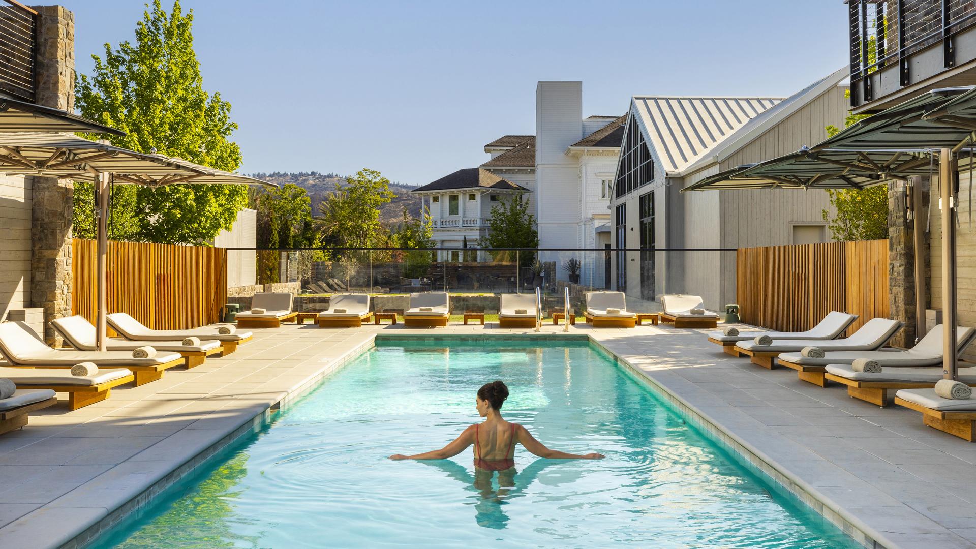 Person swimming in luxury pool, sunny day