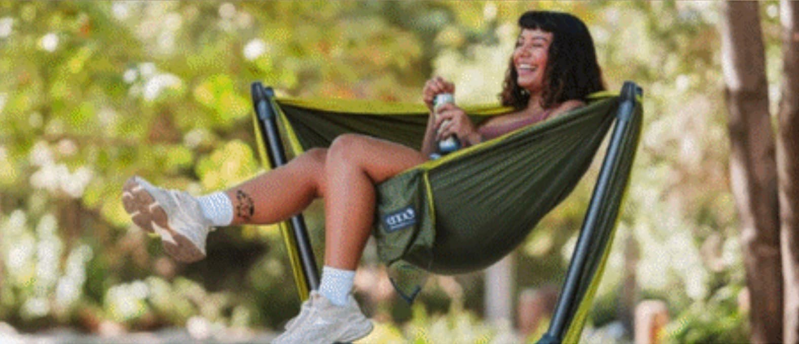 Woman relaxing in green hammock outdoors