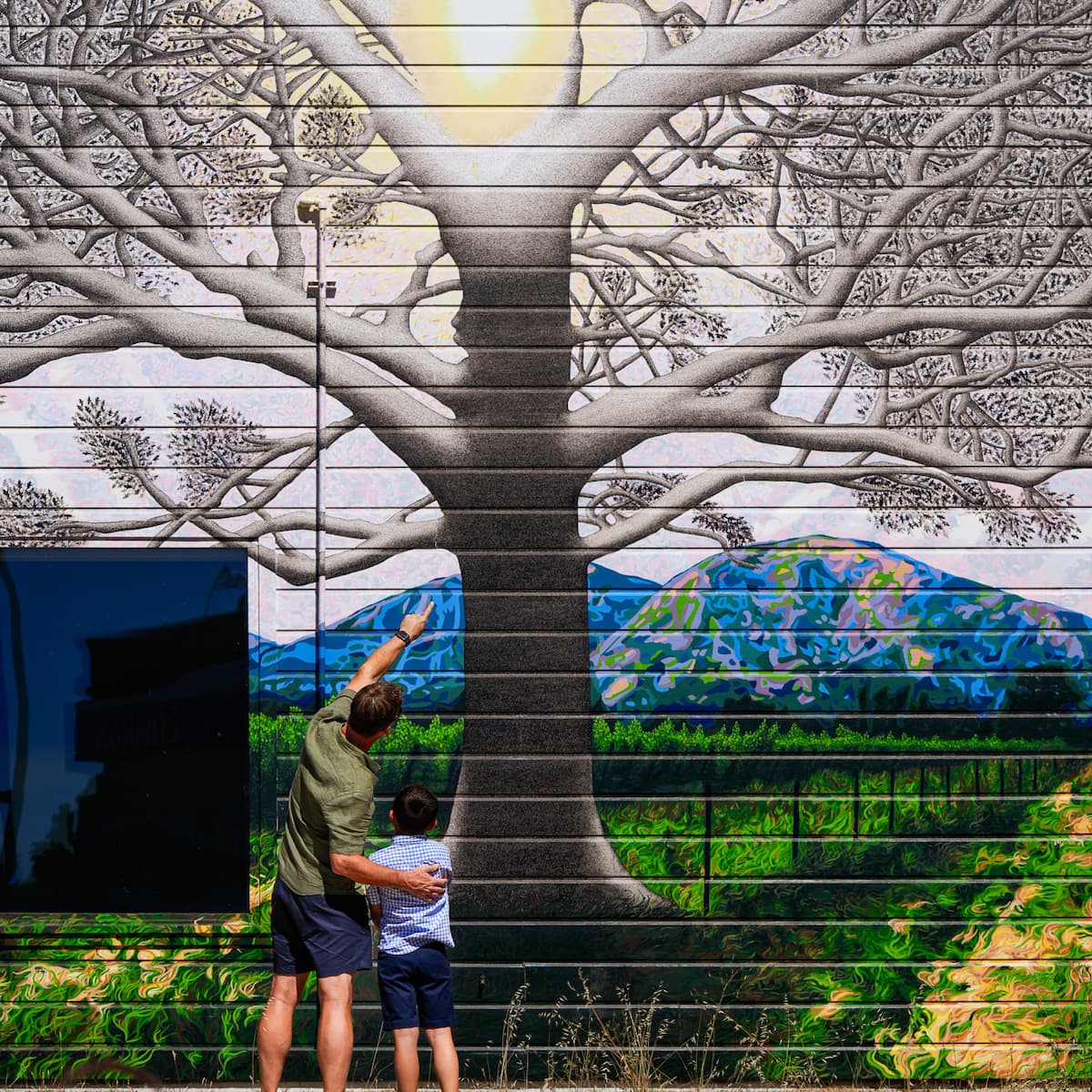 Man and child viewing tree mural