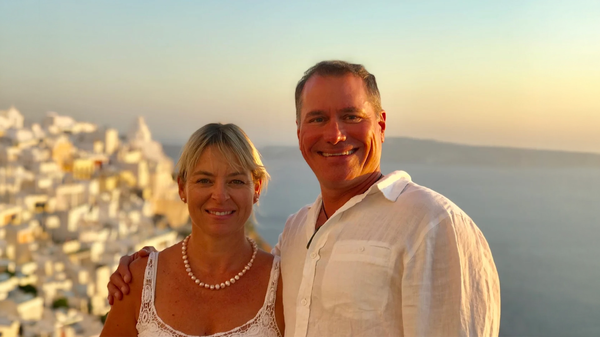 Smiling couple overlooking a coastal town at sunset