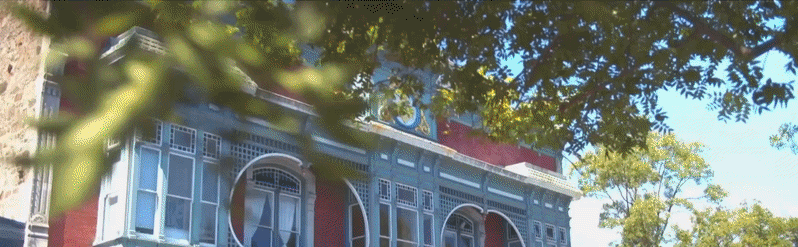 Historic building facade with arched windows and trees