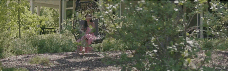 Child sitting on hanging chair in garden