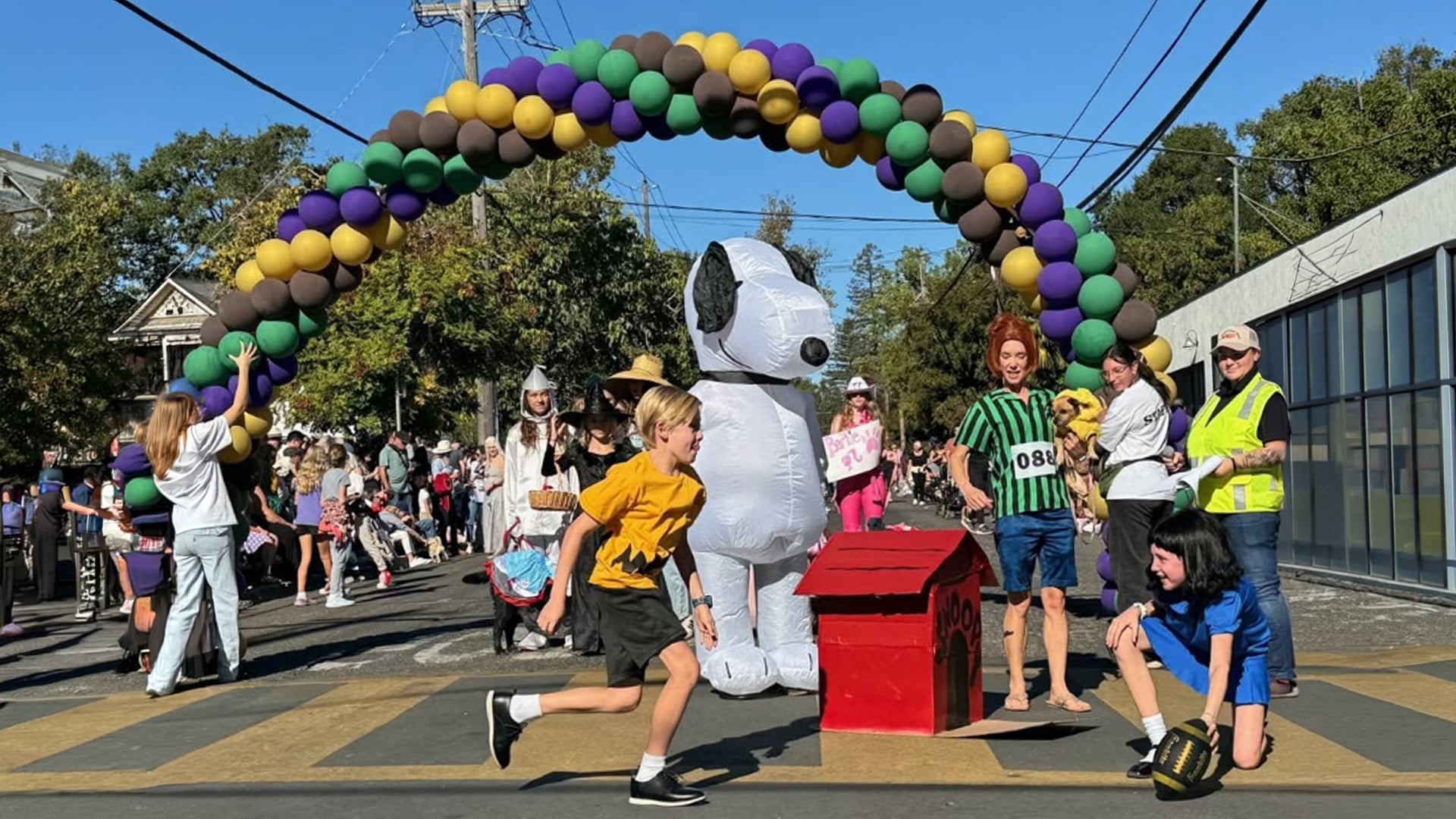 Snoopy costume beneath colorful balloon arch at community parade