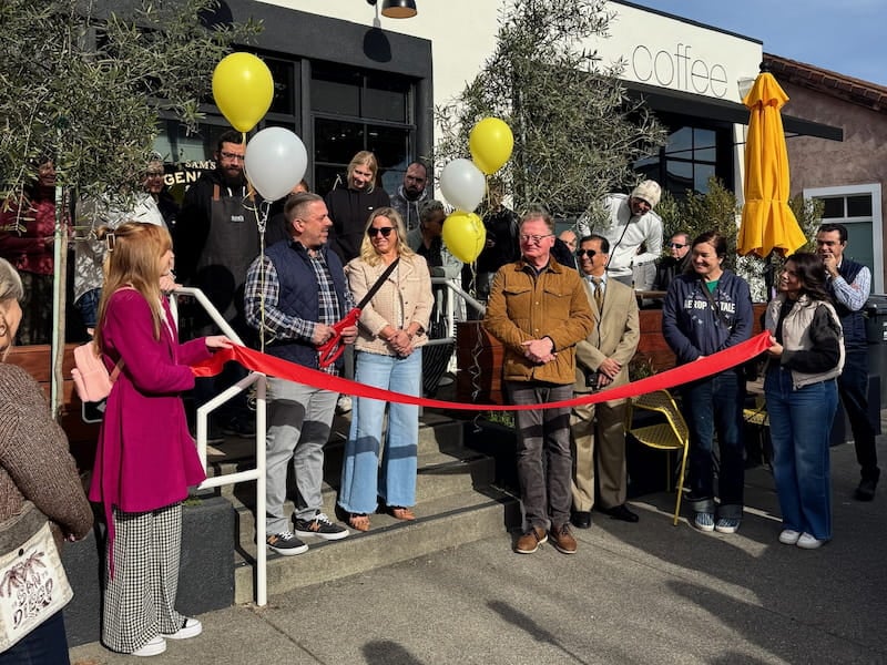 People at a ribbon-cutting ceremony outside a cafe.