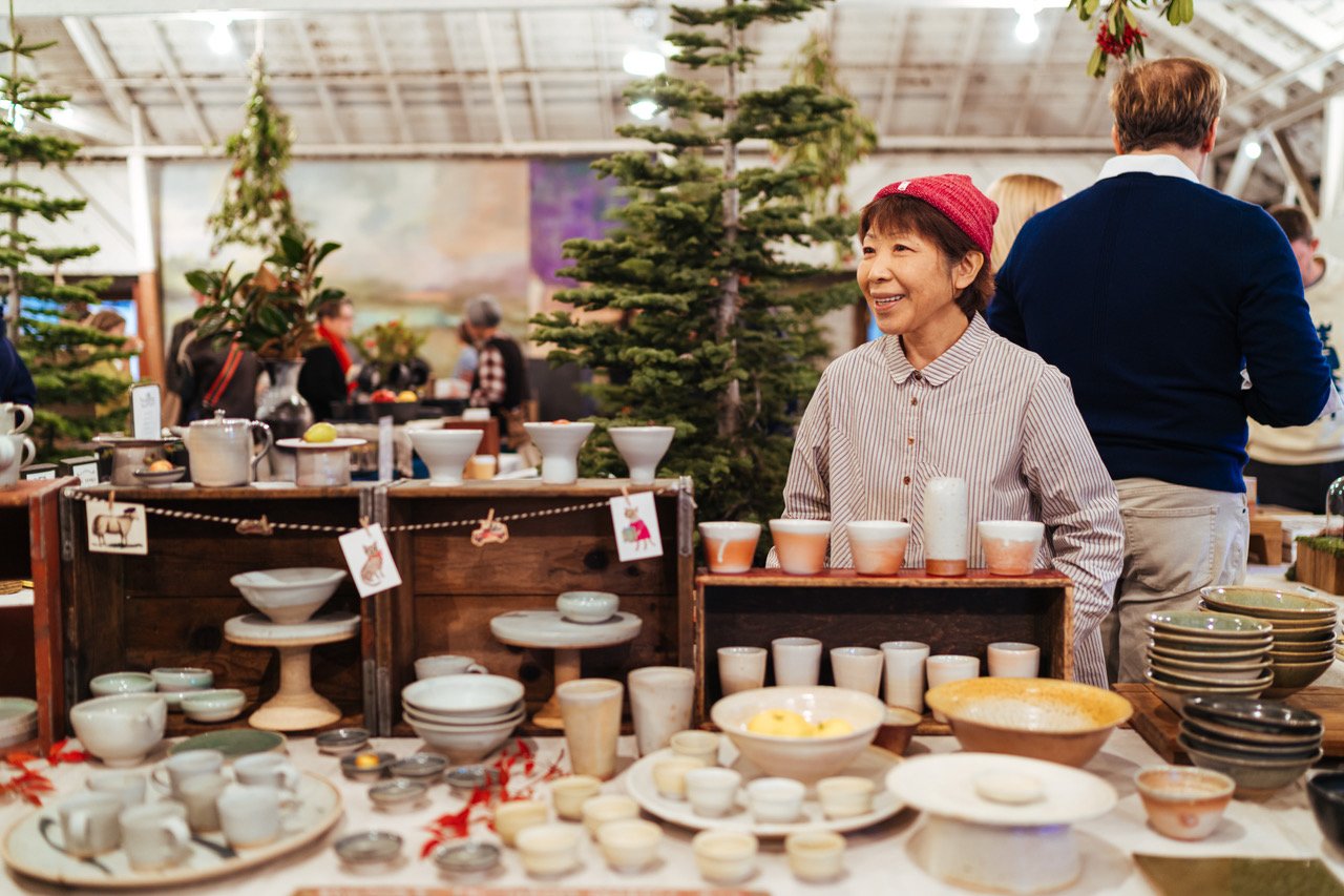 Woman selling pottery at a festive market.