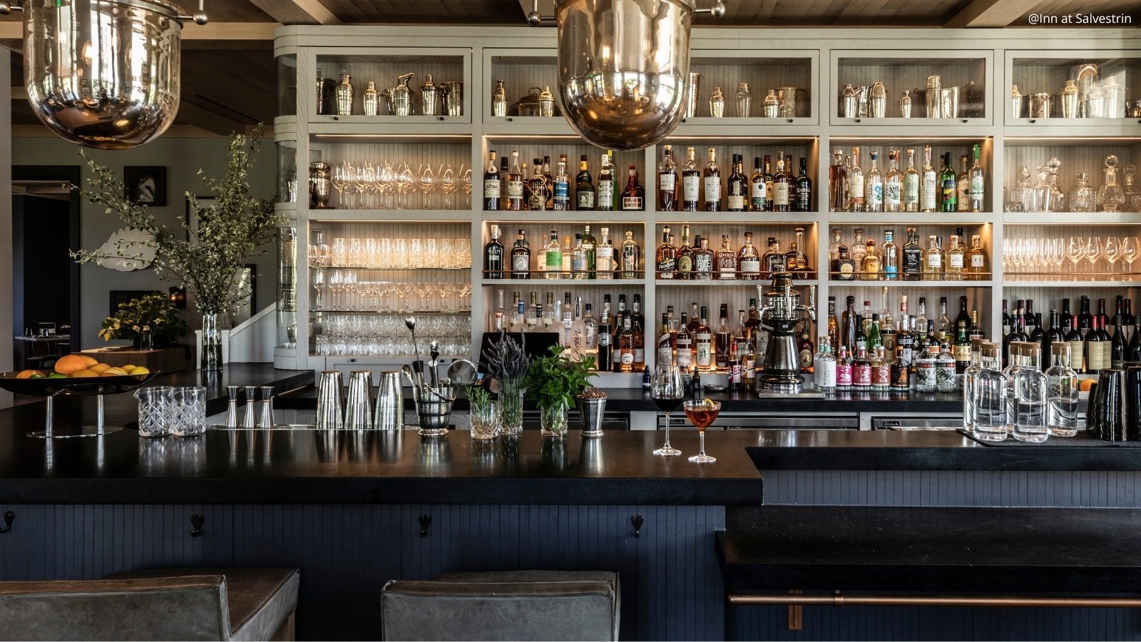 Modern bar with bottles and glassware displayed.