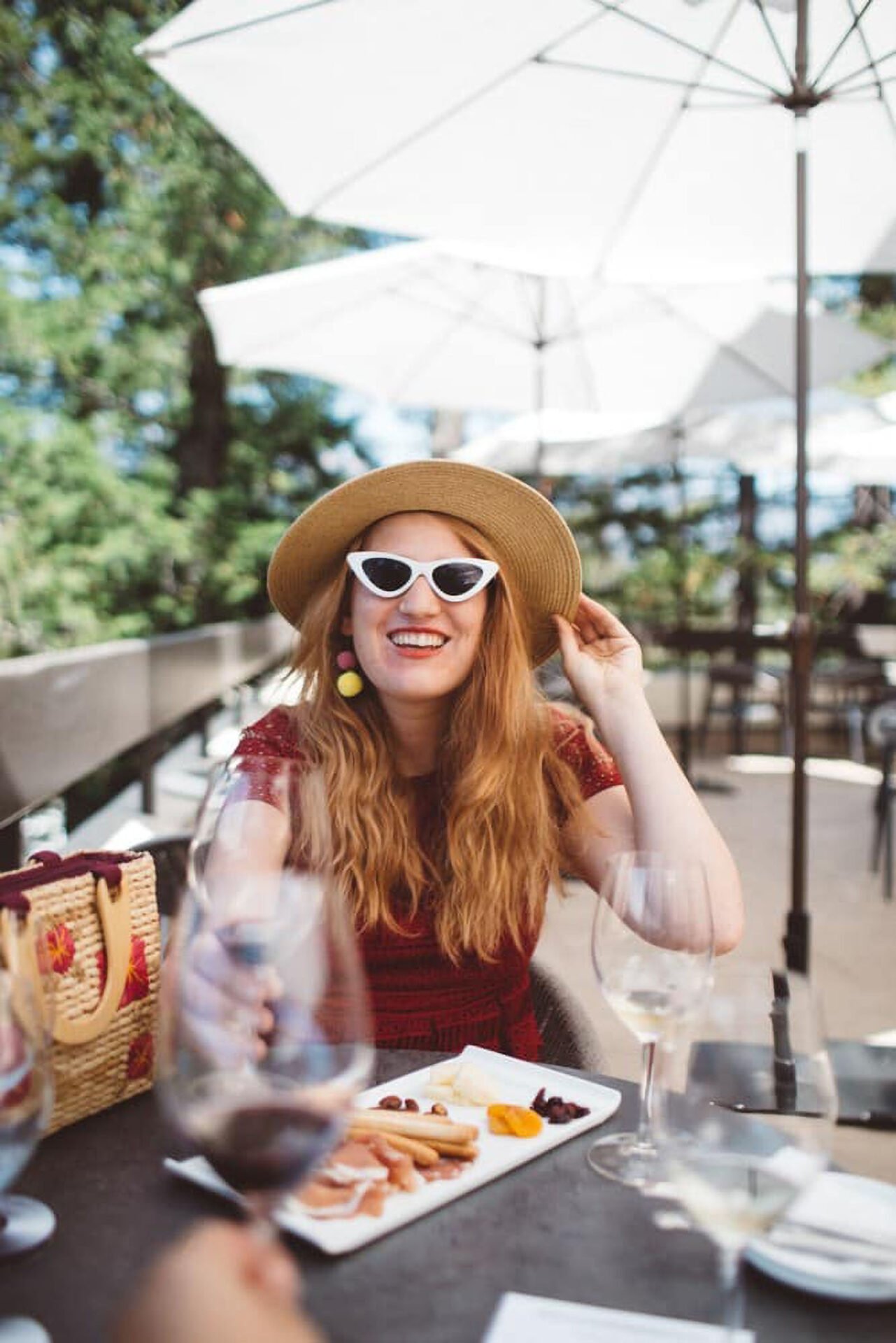Woman smiling outdoors with sunglasses and hat