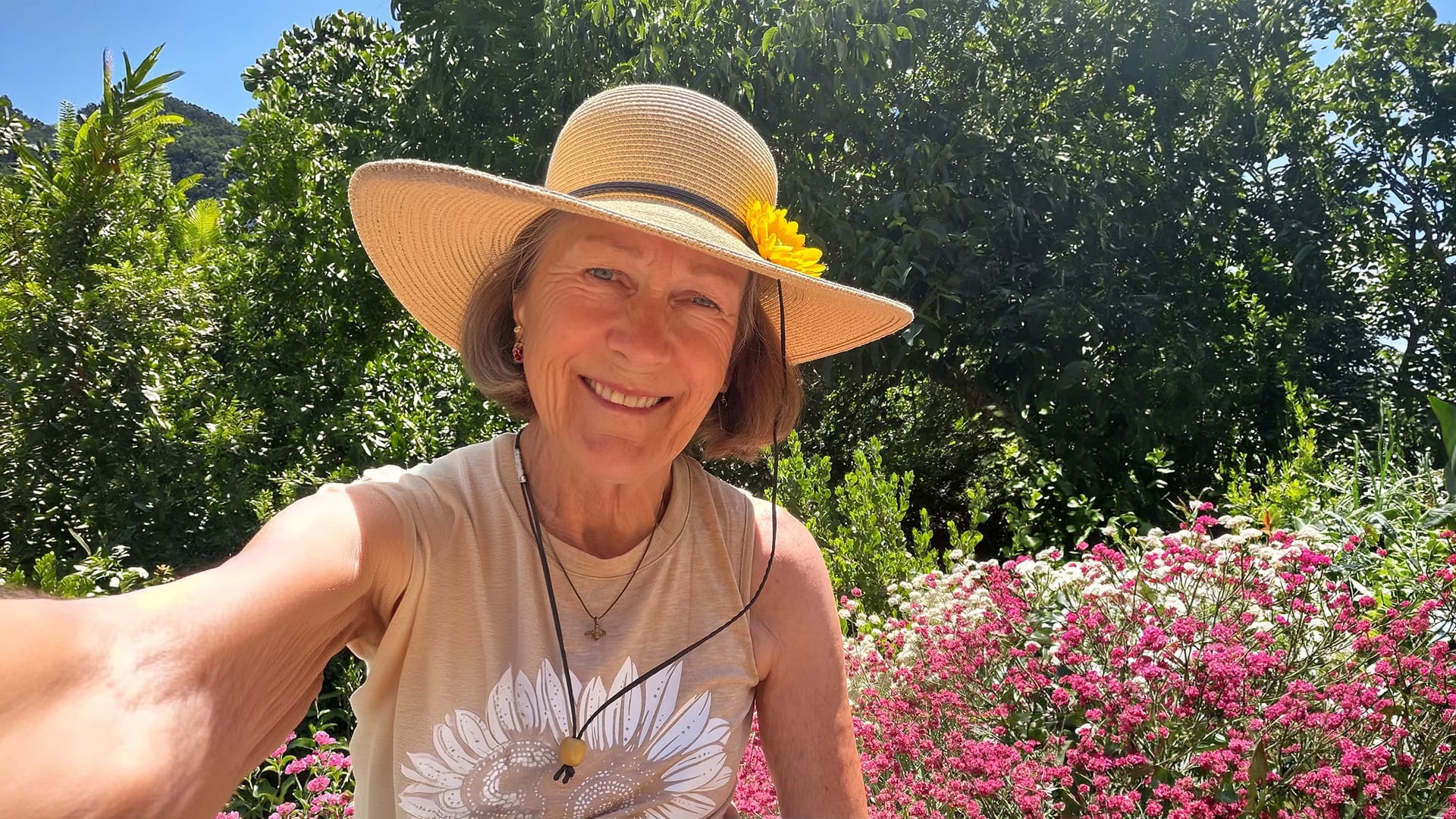 Smiling woman in straw hat in flower garden