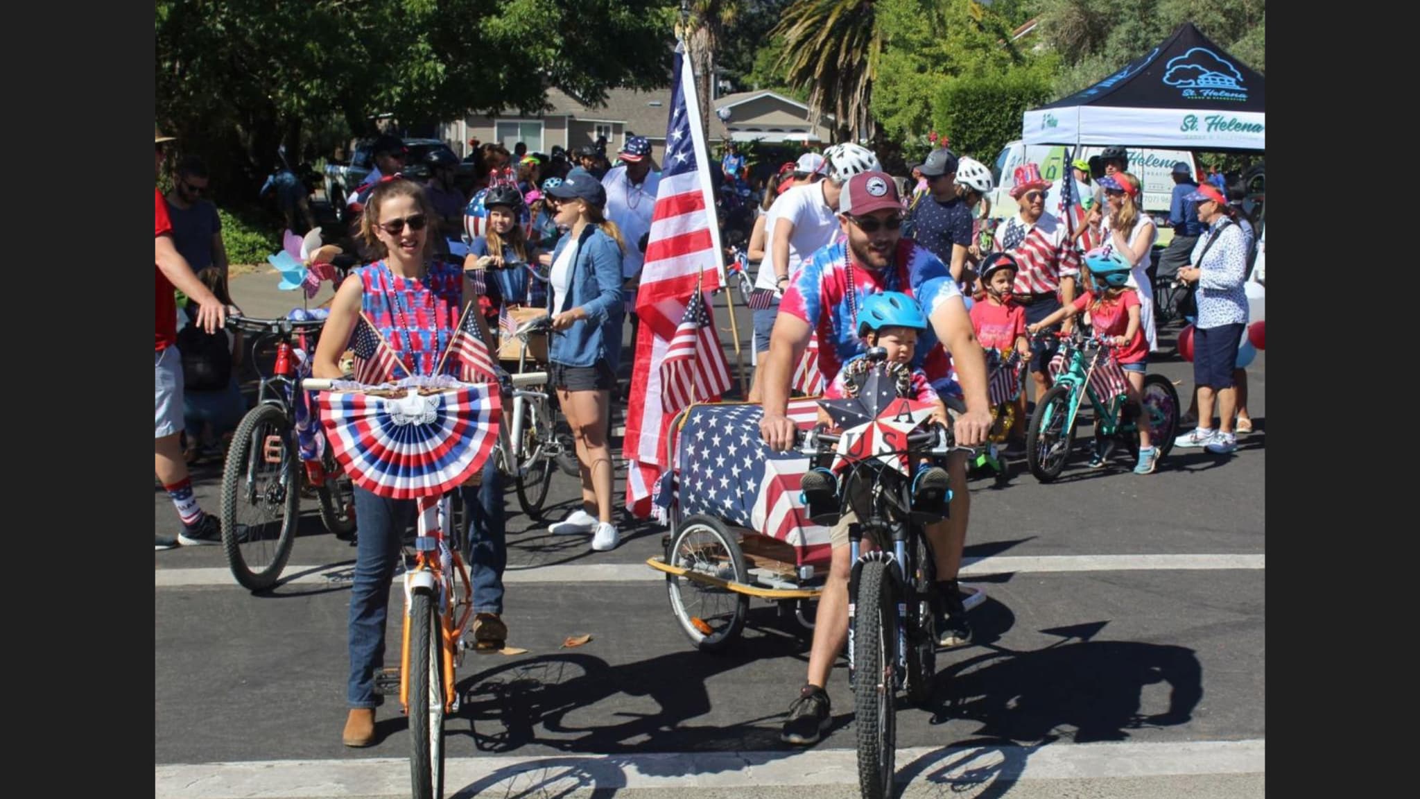 Families riding decorated bikes in patriotic parade