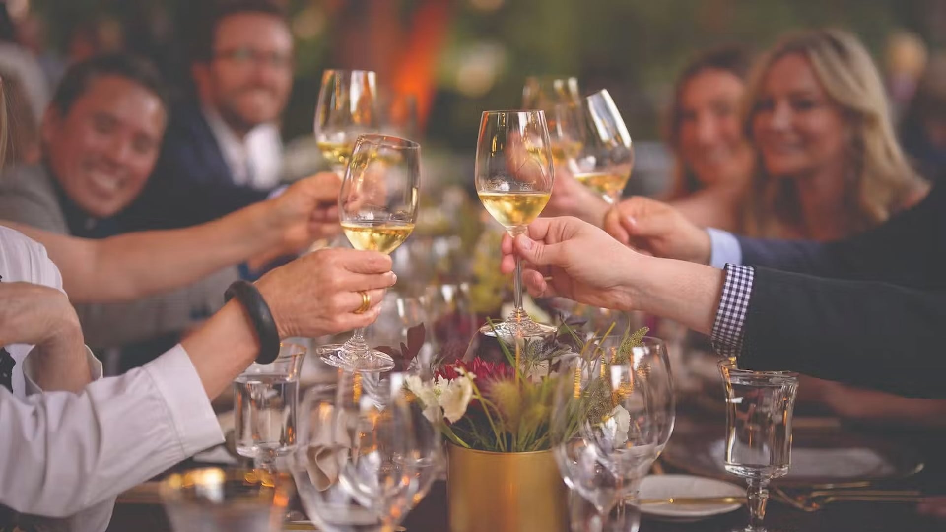 Friends toasting with white wine at dinner table