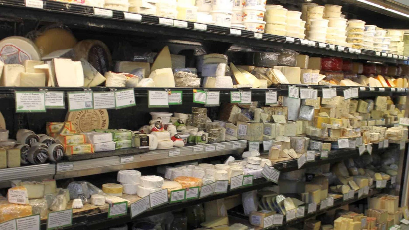 Various cheeses displayed on grocery store shelves.