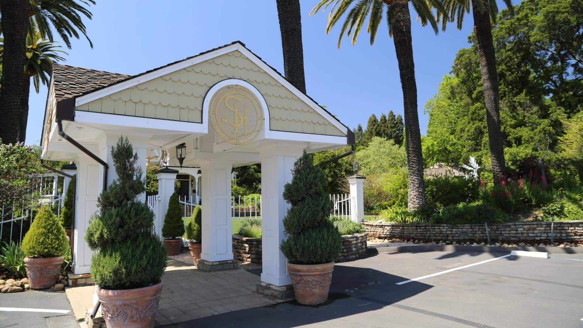 Elegant entrance with potted trees and palm backdrop.