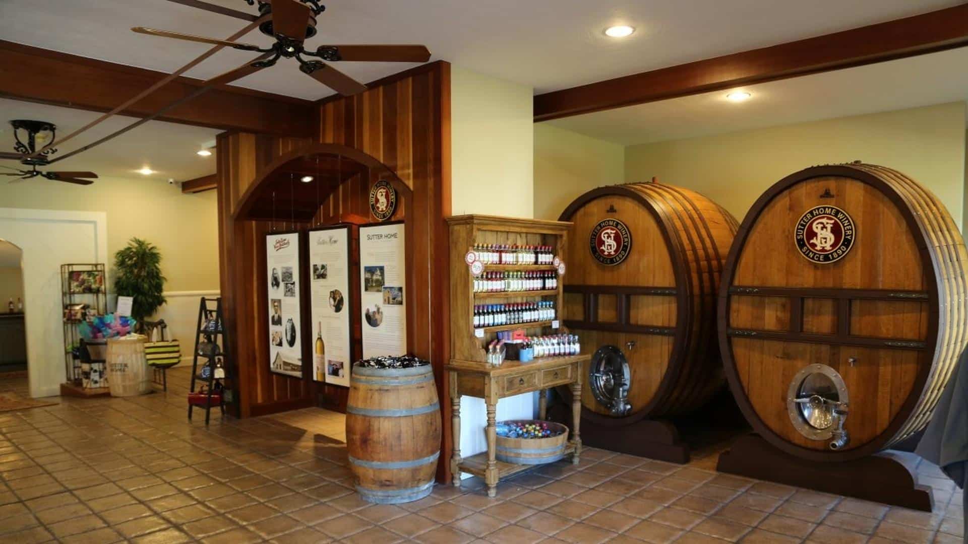 Winery tasting room with large oak barrels and displays.