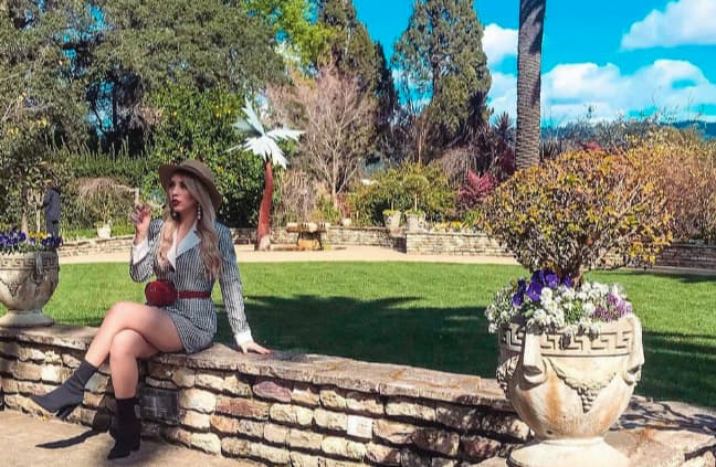 Woman sitting on stone wall in garden