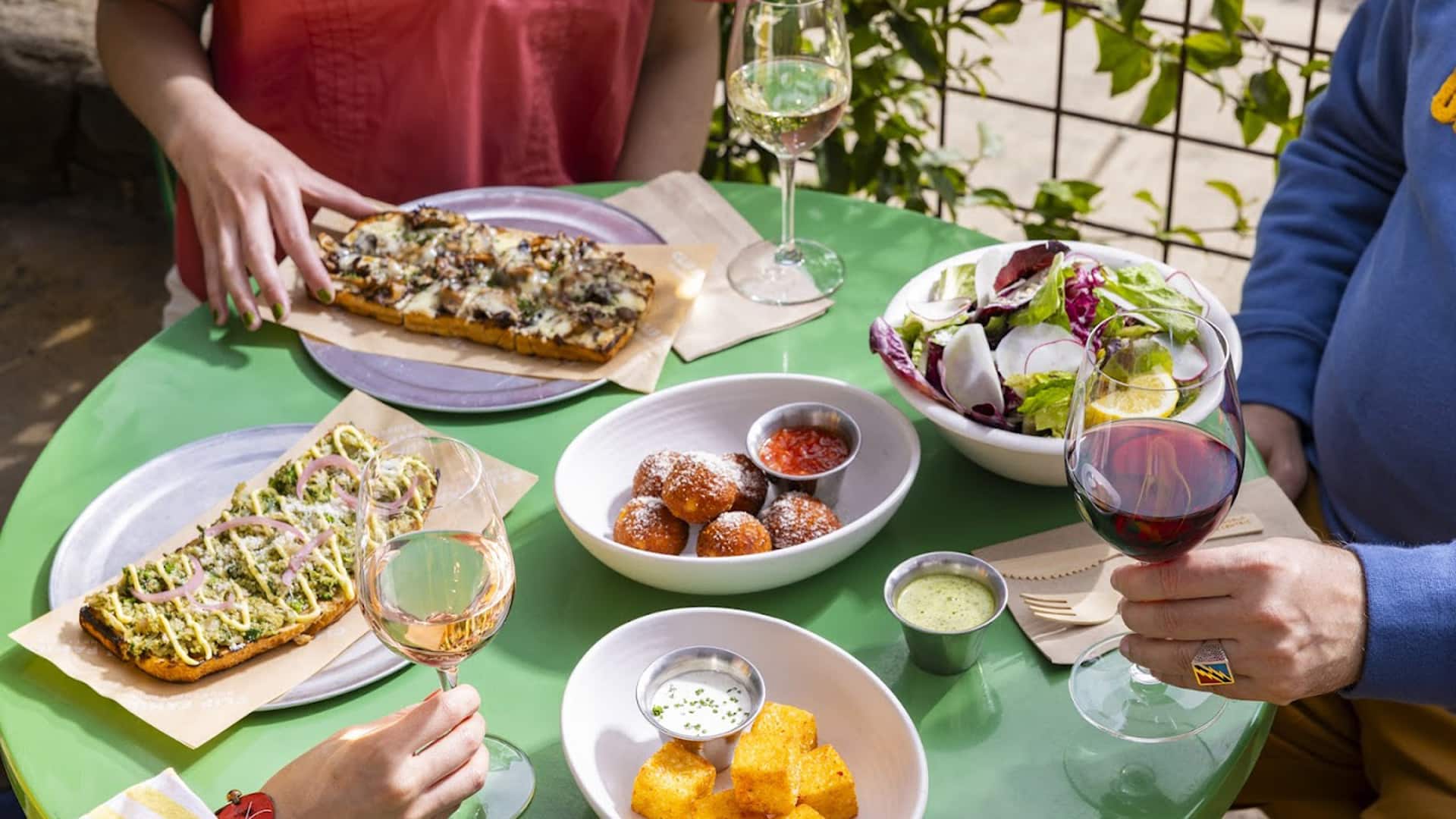 Outdoor dining with flatbreads, salad, and wine.
