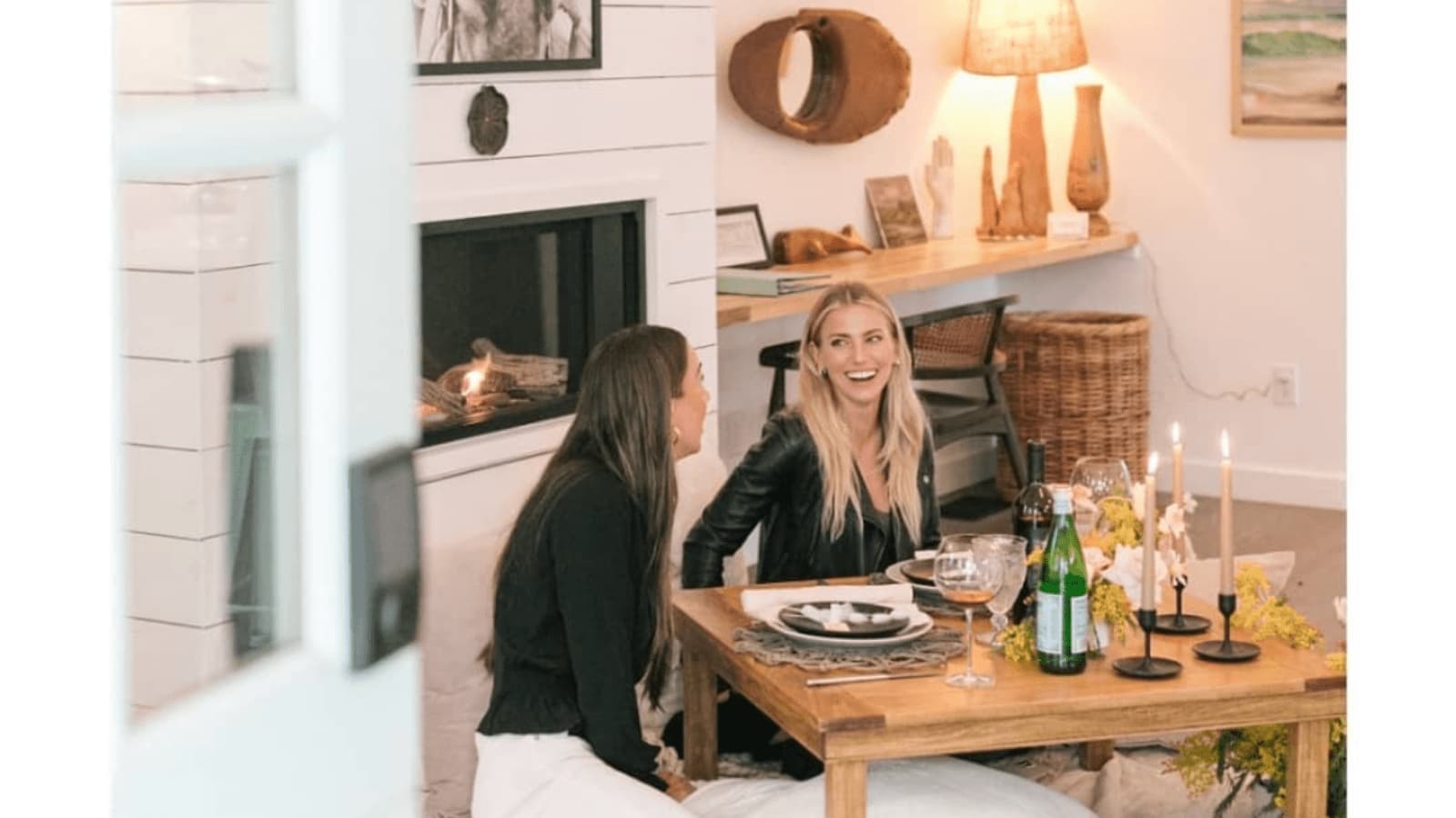 Two women dining by a cozy fireplace.