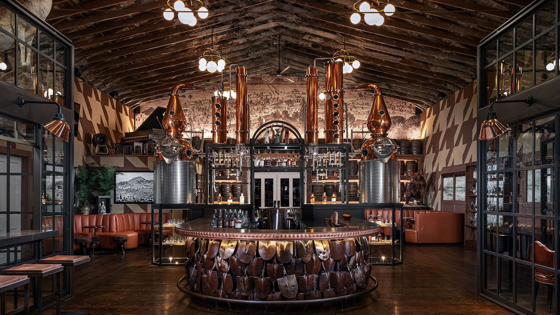Rustic distillery bar with copper stills and seating.