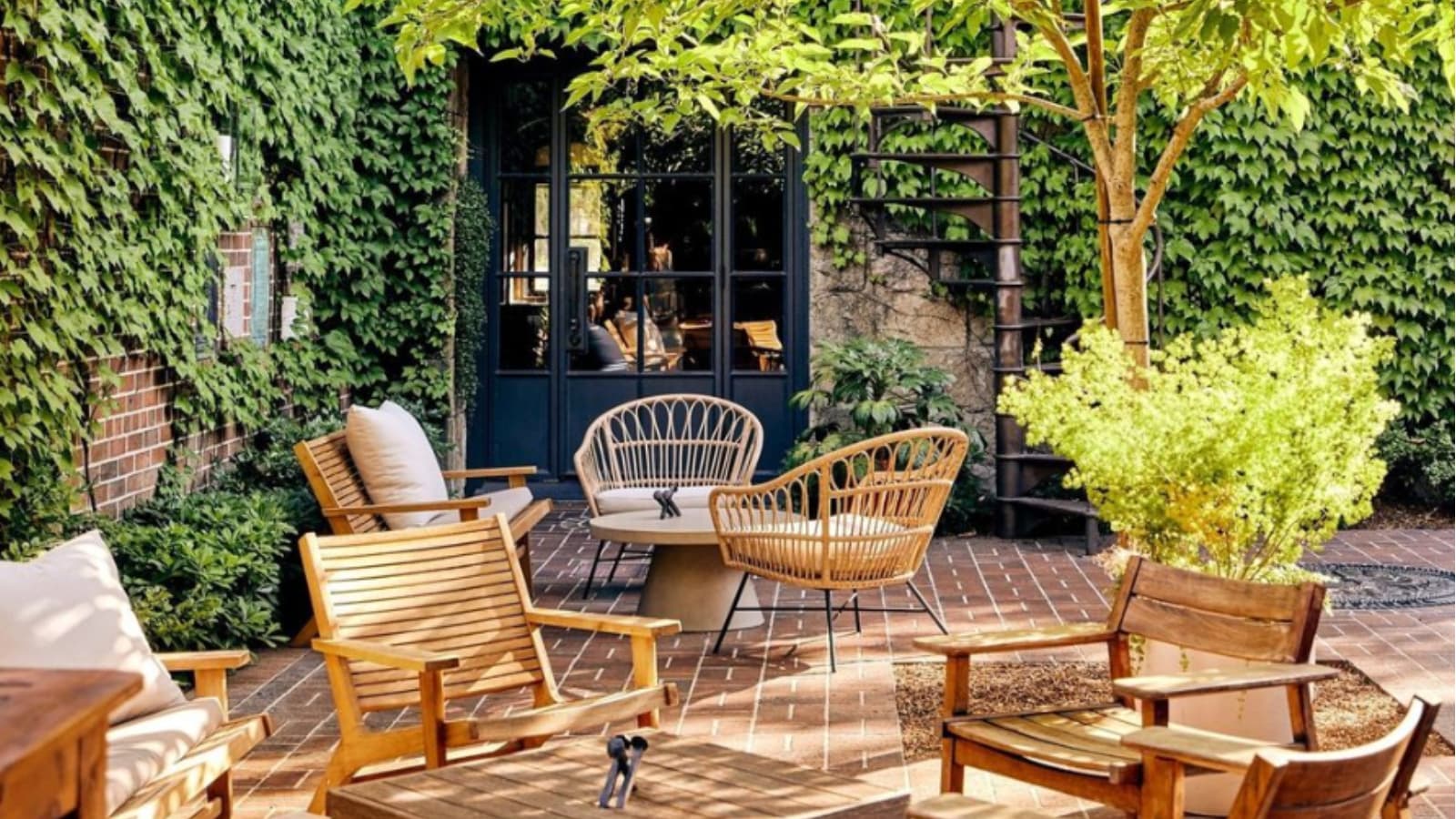 Cozy patio with furniture and leafy walls.