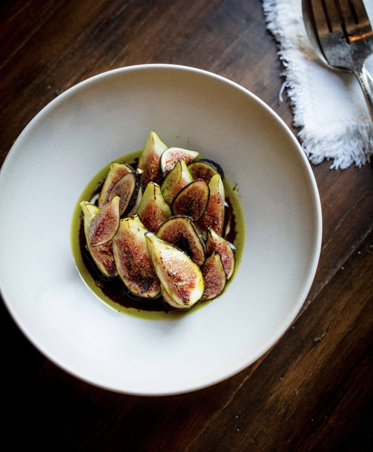 Sliced figs with drizzle in a white bowl
