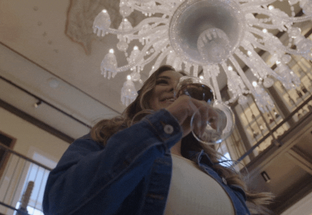 Woman drinking wine under chandelier indoors