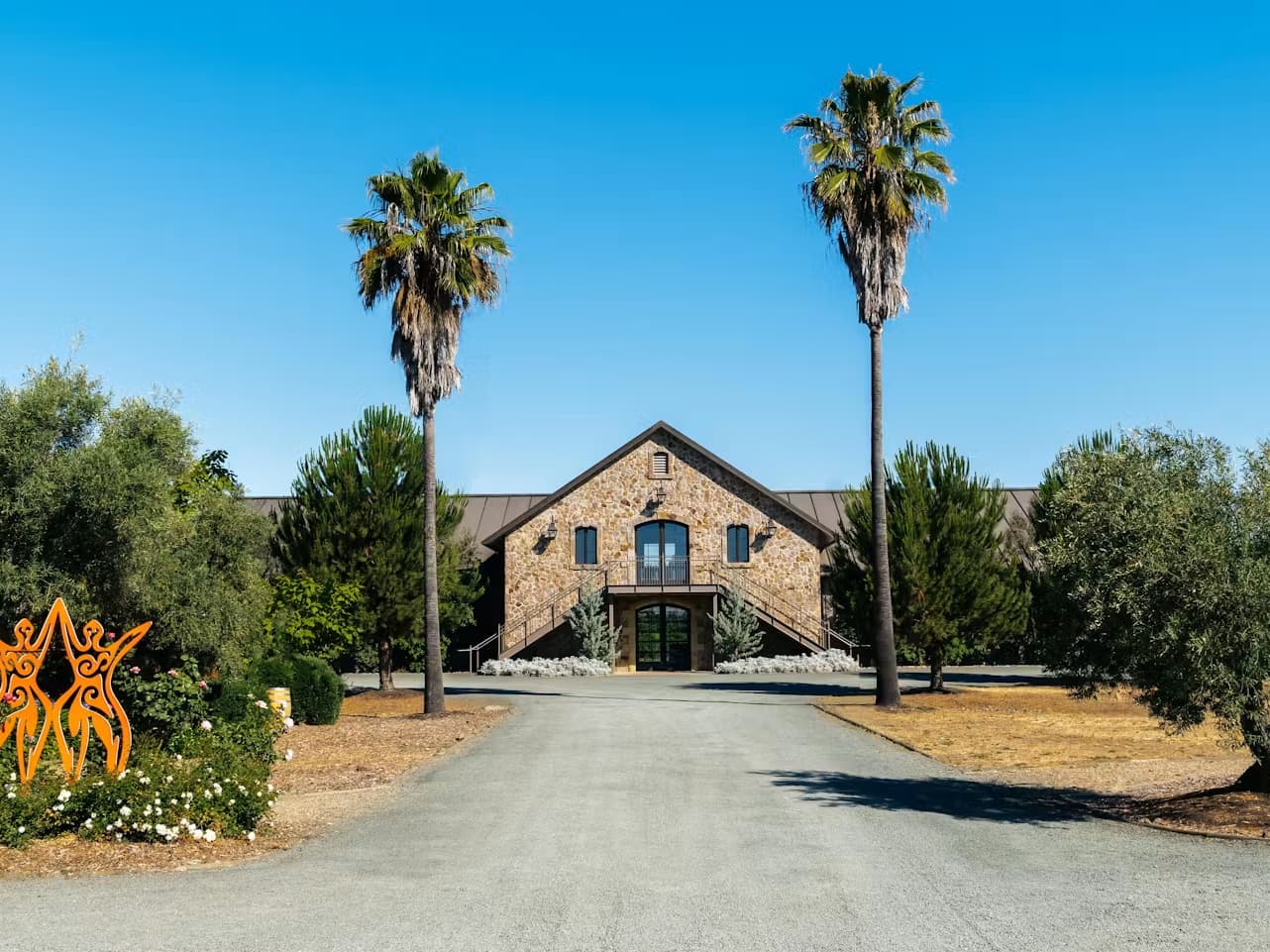 Stone estate building with palm-lined driveway