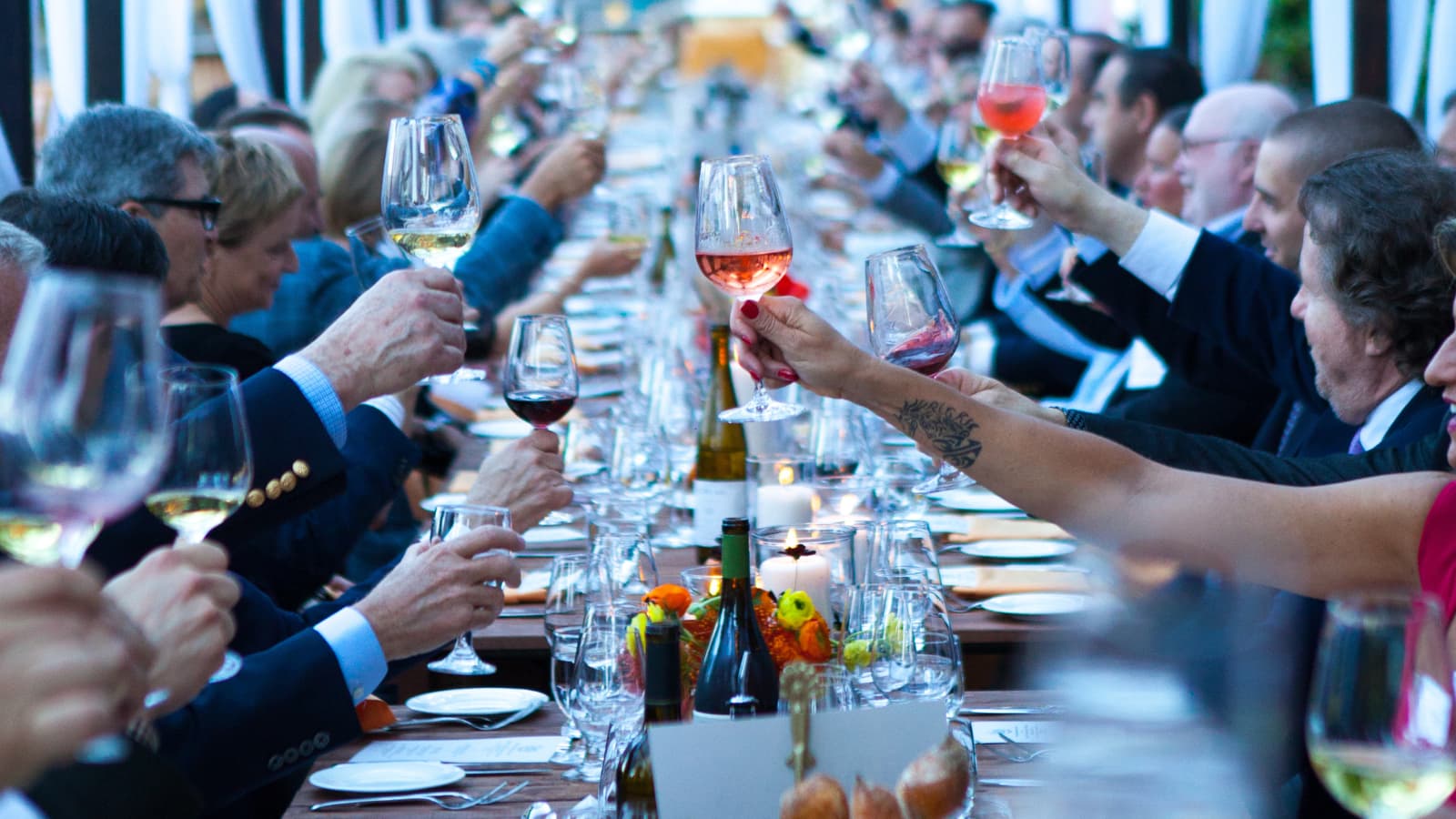 People toasting with wine at a long table.