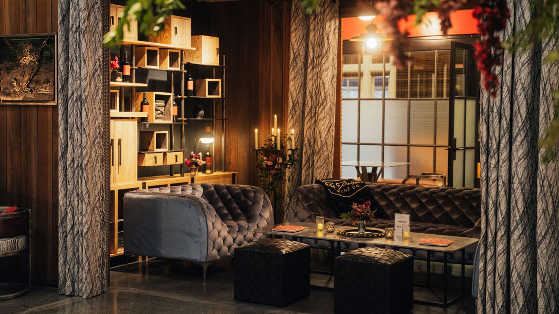 Cozy lounge with velvet sofas and wooden shelves.
